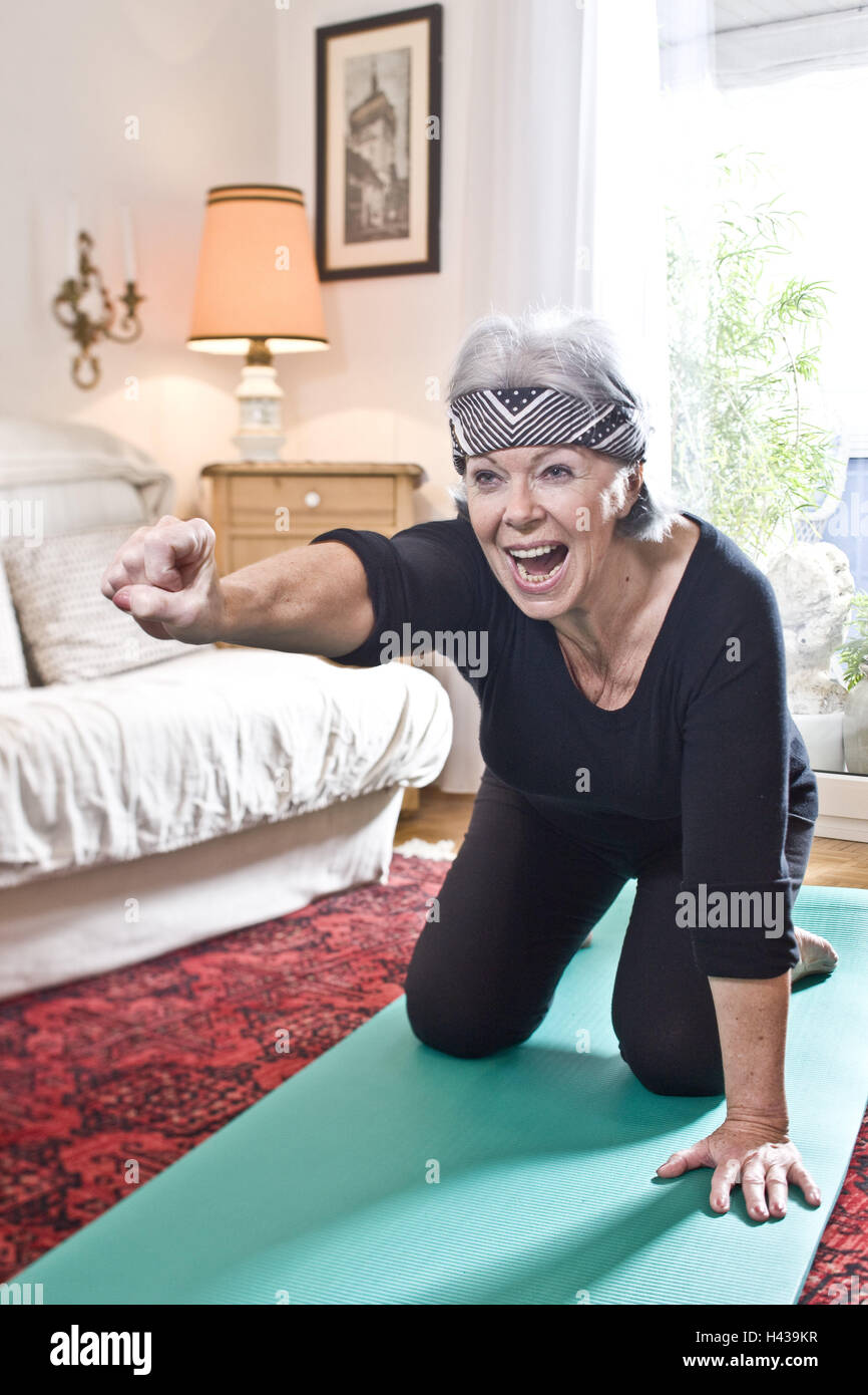 Senior donna, materassino yoga, inginocchiato, stretching, pugno, urlando,, Foto Stock
