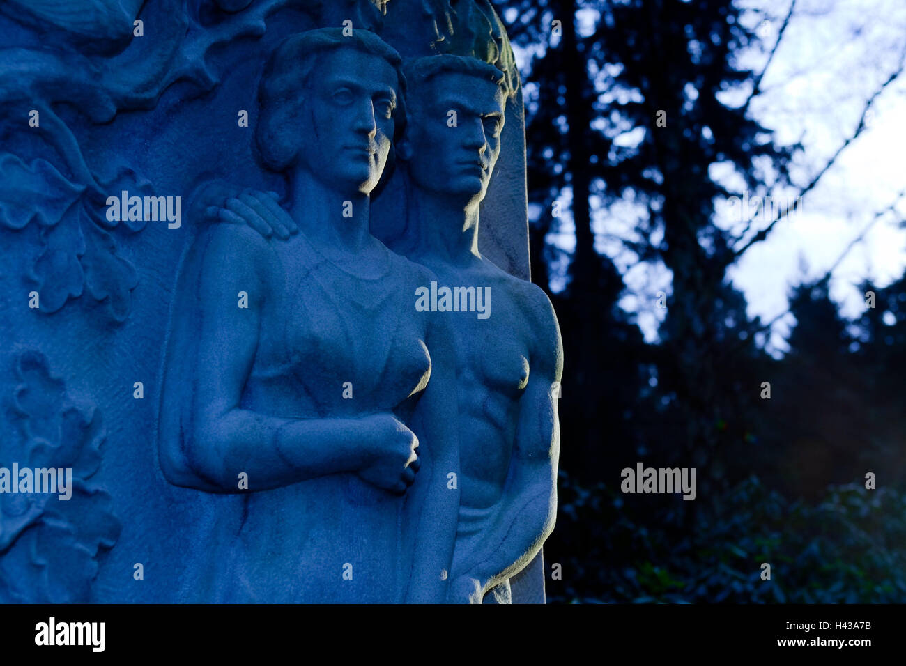 Cimitero, tomba figure, crepuscolo, pietra tombale, tomba, icona, dolore, morte, dimissioni, BT, statua, figure, pietra, figure in pietra, uomo donna, giovane, luce e ombra, alberi, sera, al tramonto, monumento, oscurità, blu Foto Stock