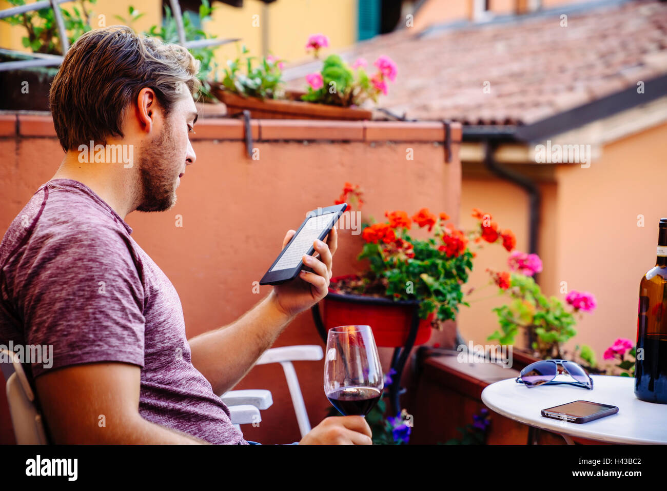 Uomo caucasico la lettura digitale compressa di bere vino rosso Foto Stock