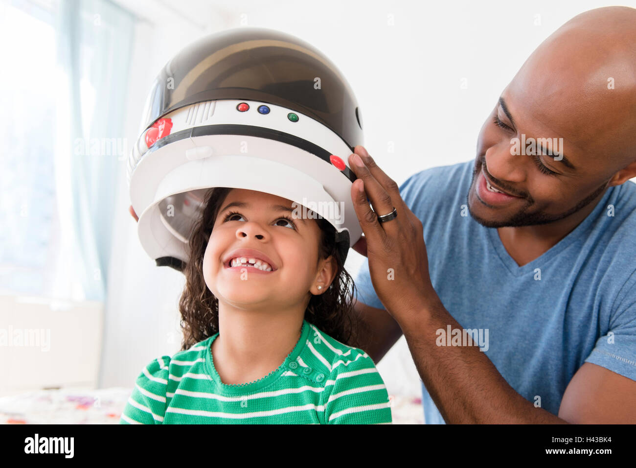 Padre immissione astronauta casco su figlia Foto Stock