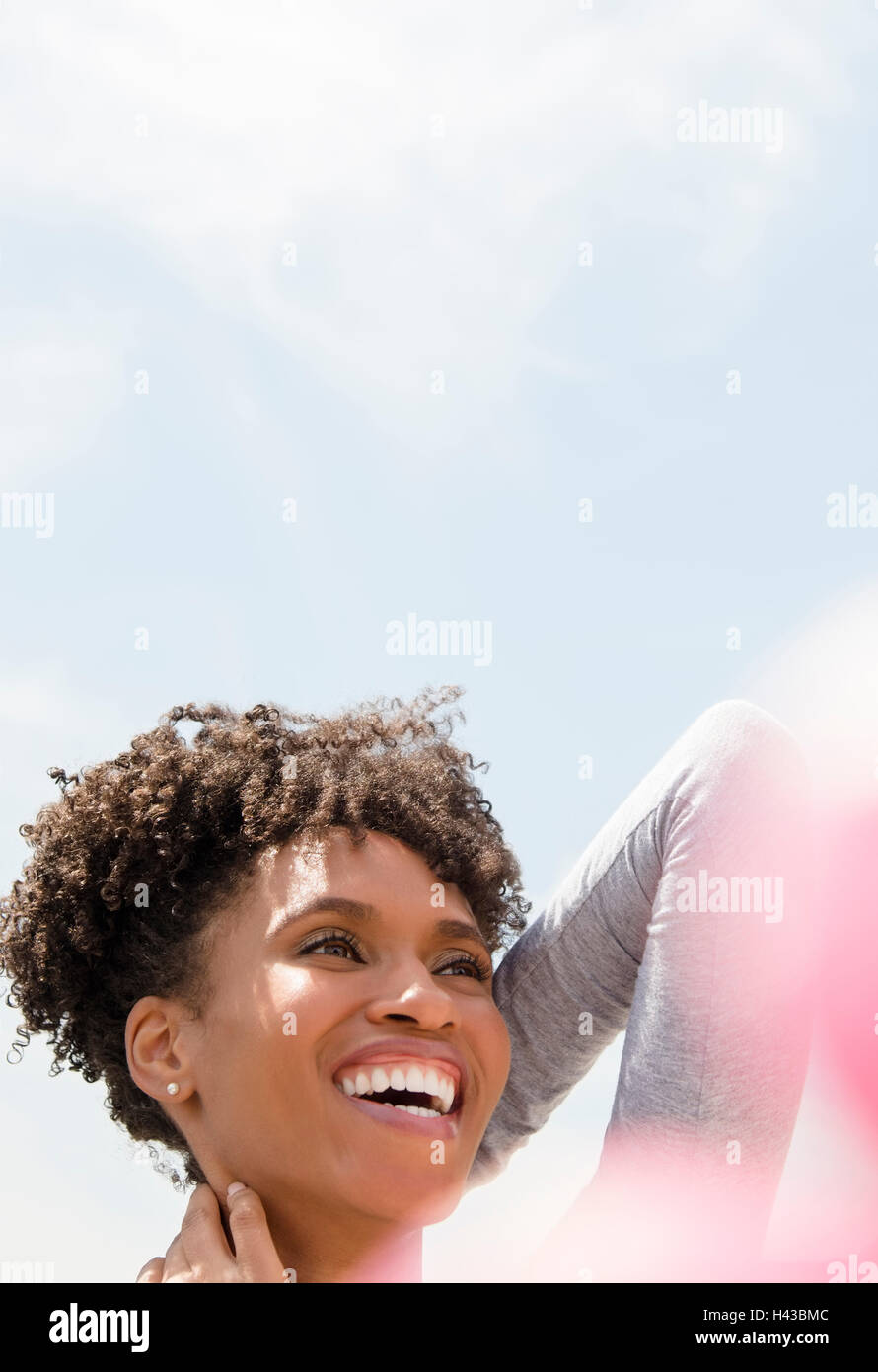 Sorridente donna nera collo di sfregamento all'aperto Foto Stock