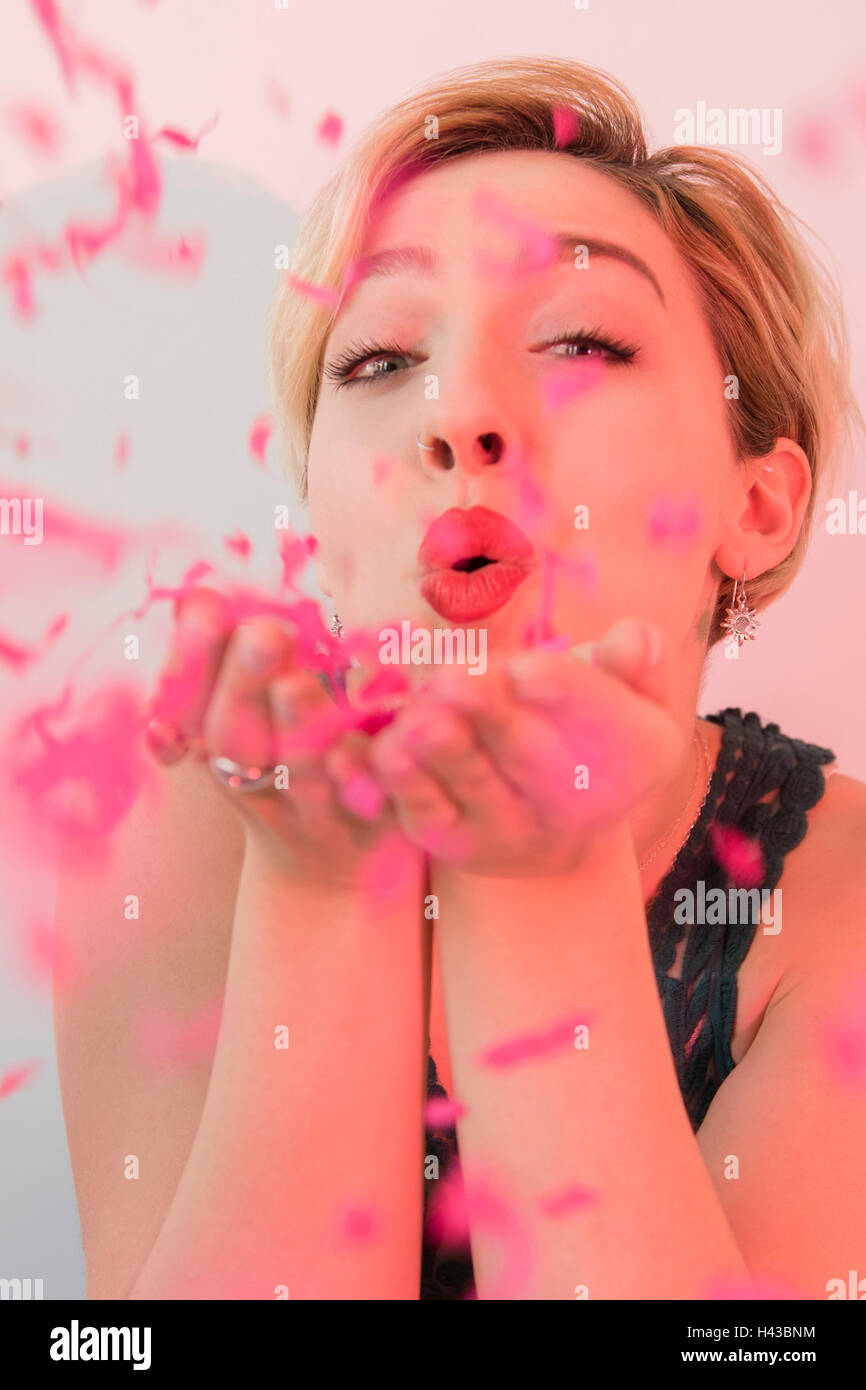 La donna caucasica soffiaggio coriandoli rosa Foto Stock