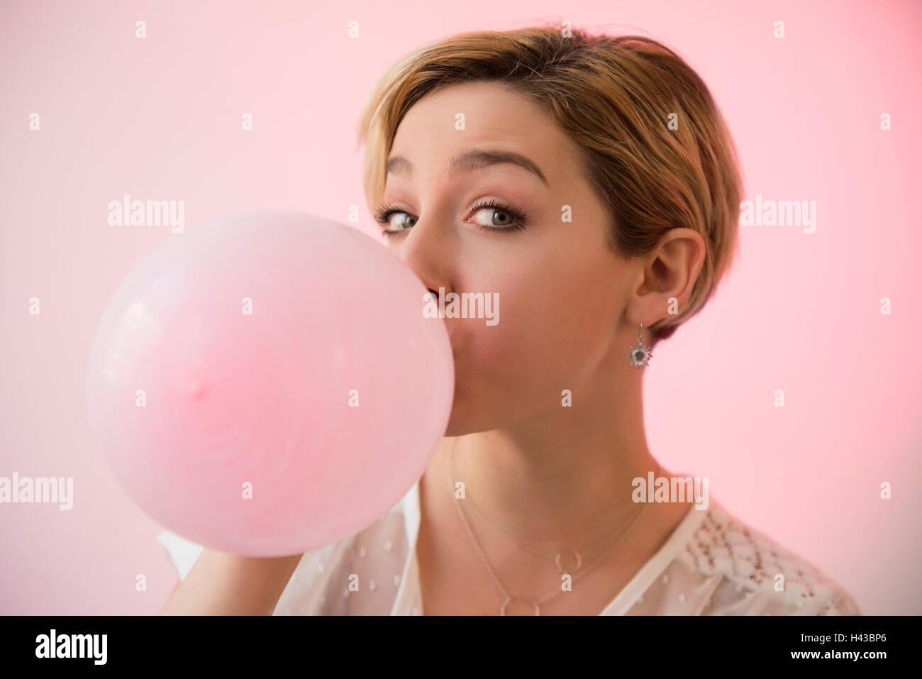 La donna caucasica il gonfiaggio del palloncino rosa Foto Stock