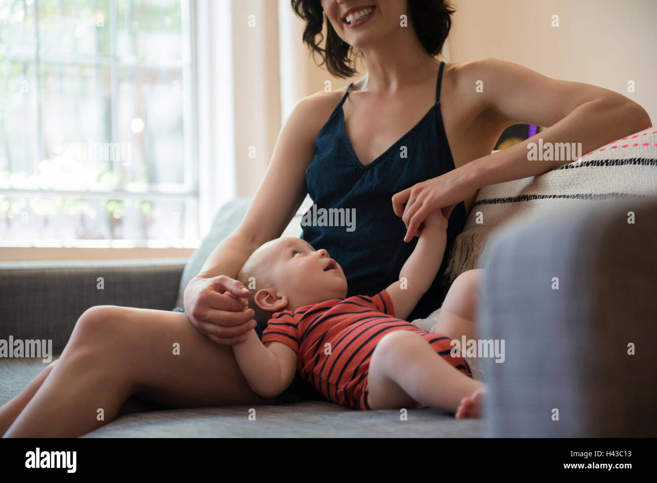 Madre caucasica seduto sul divano per mano del neonato figlio Foto Stock