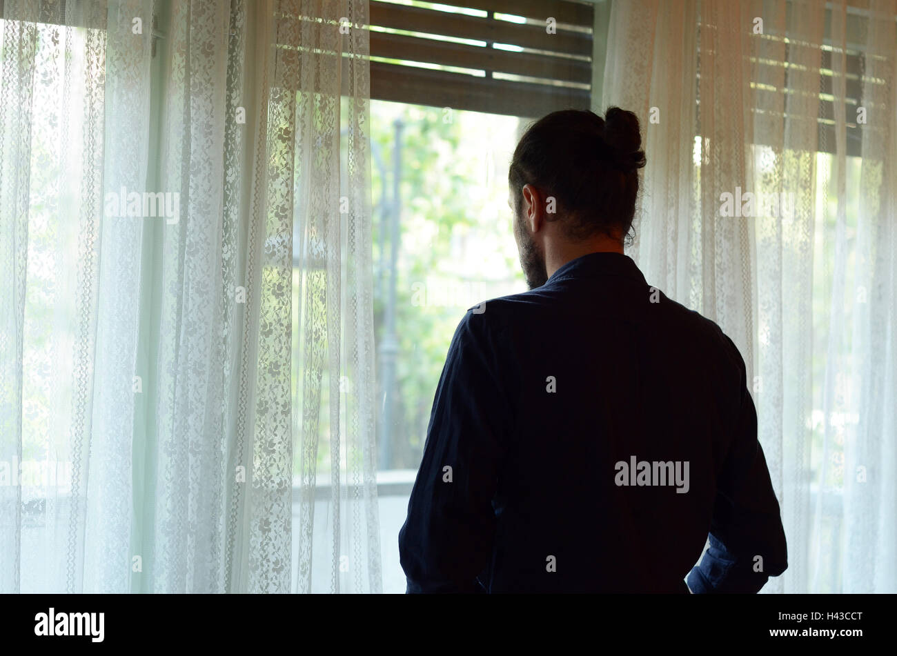 Uomo che guarda fuori della finestra Foto Stock