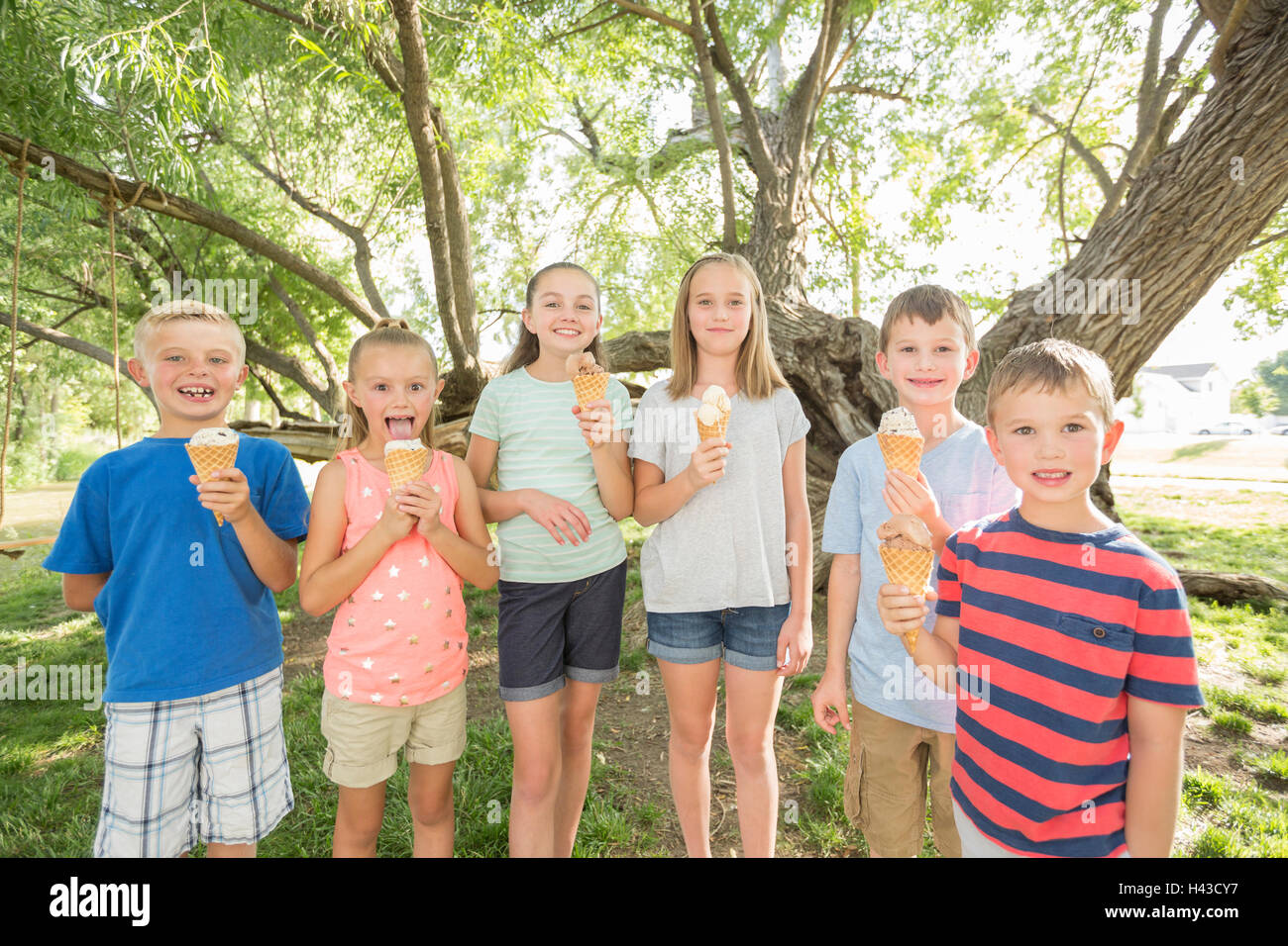 Caucasian i ragazzi e le ragazze a mangiare il gelato coni Foto Stock