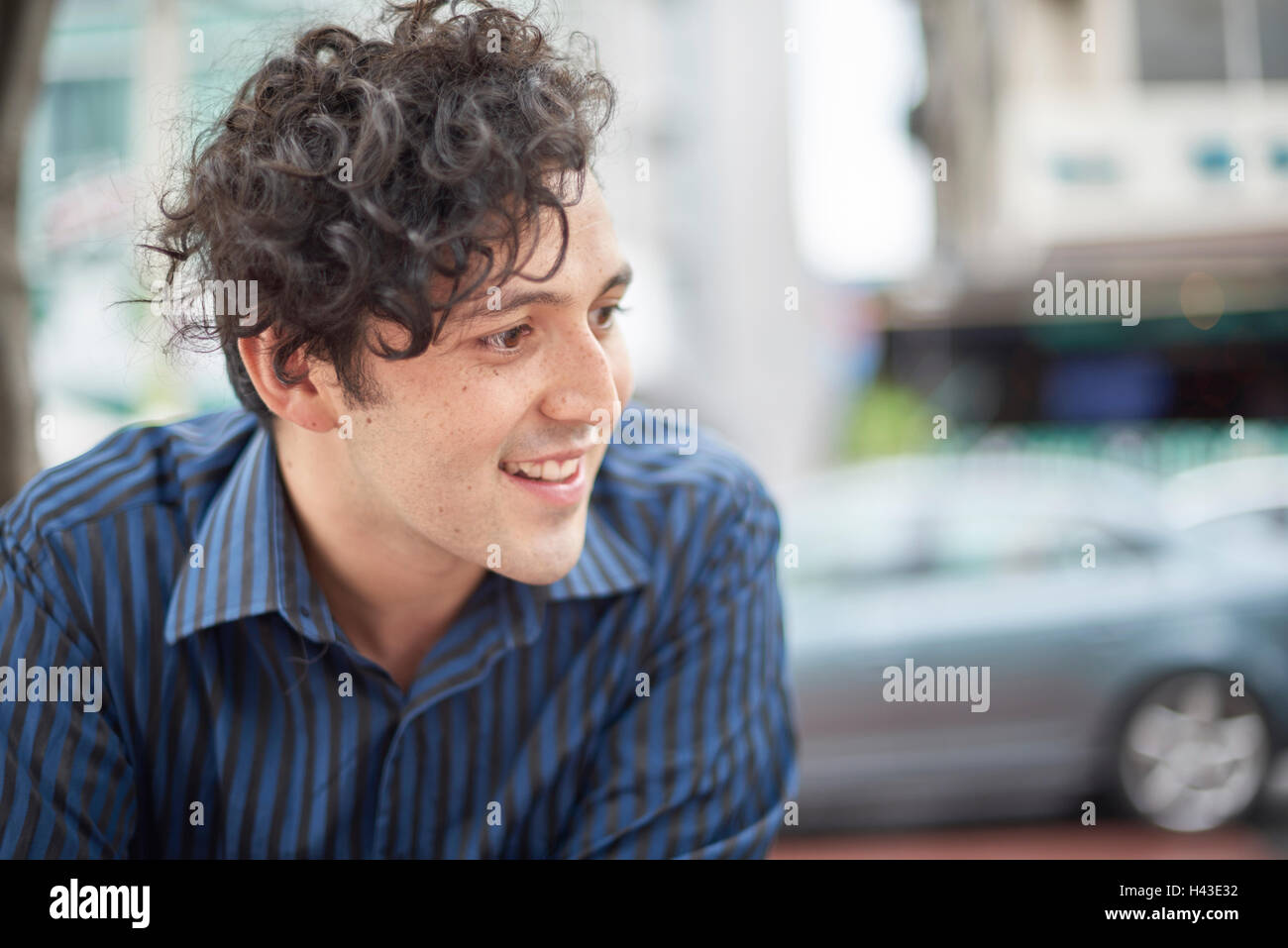 Sorridente uomo ispanico con capelli ricci Foto Stock