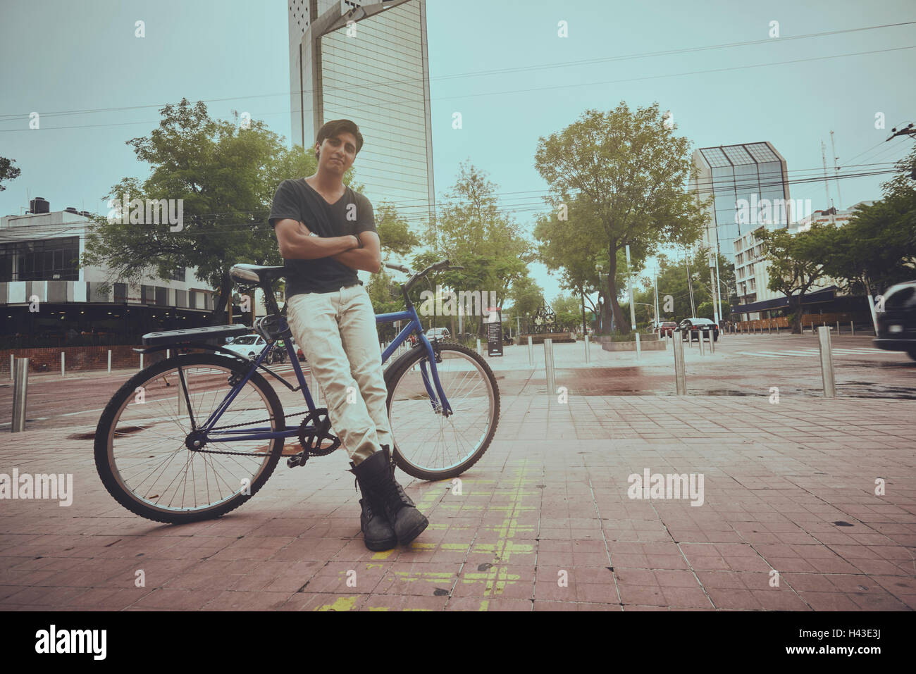 Sorridente uomo ispanico appoggiata sulla bicicletta in città Foto Stock