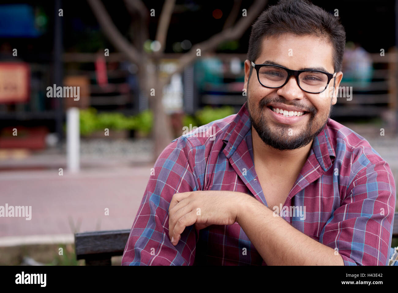 Sorridente uomo ispanico con la barba seduto su un banco di lavoro Foto Stock