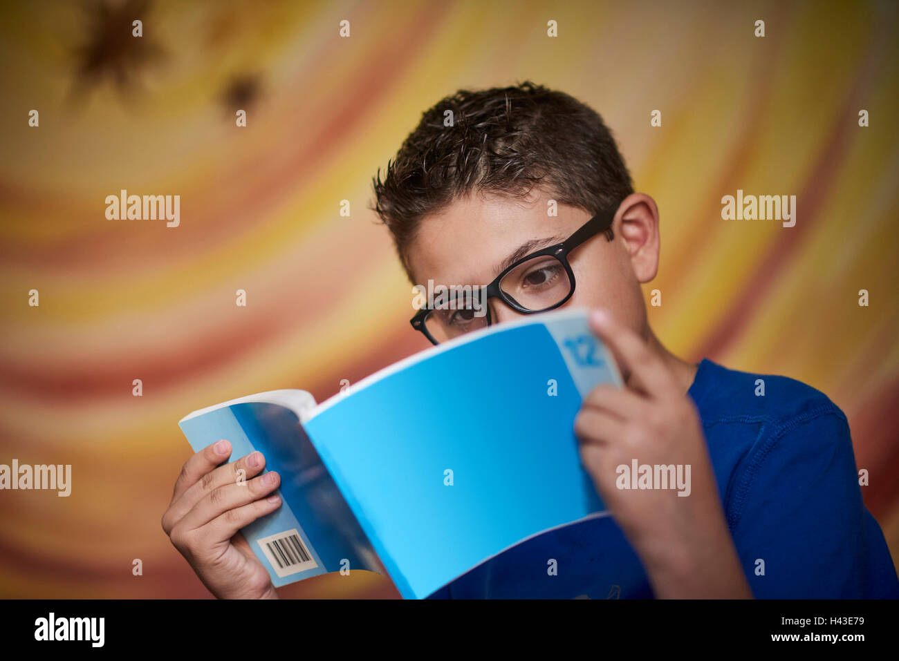 Ispanico ragazzo lettura libro blu Foto Stock