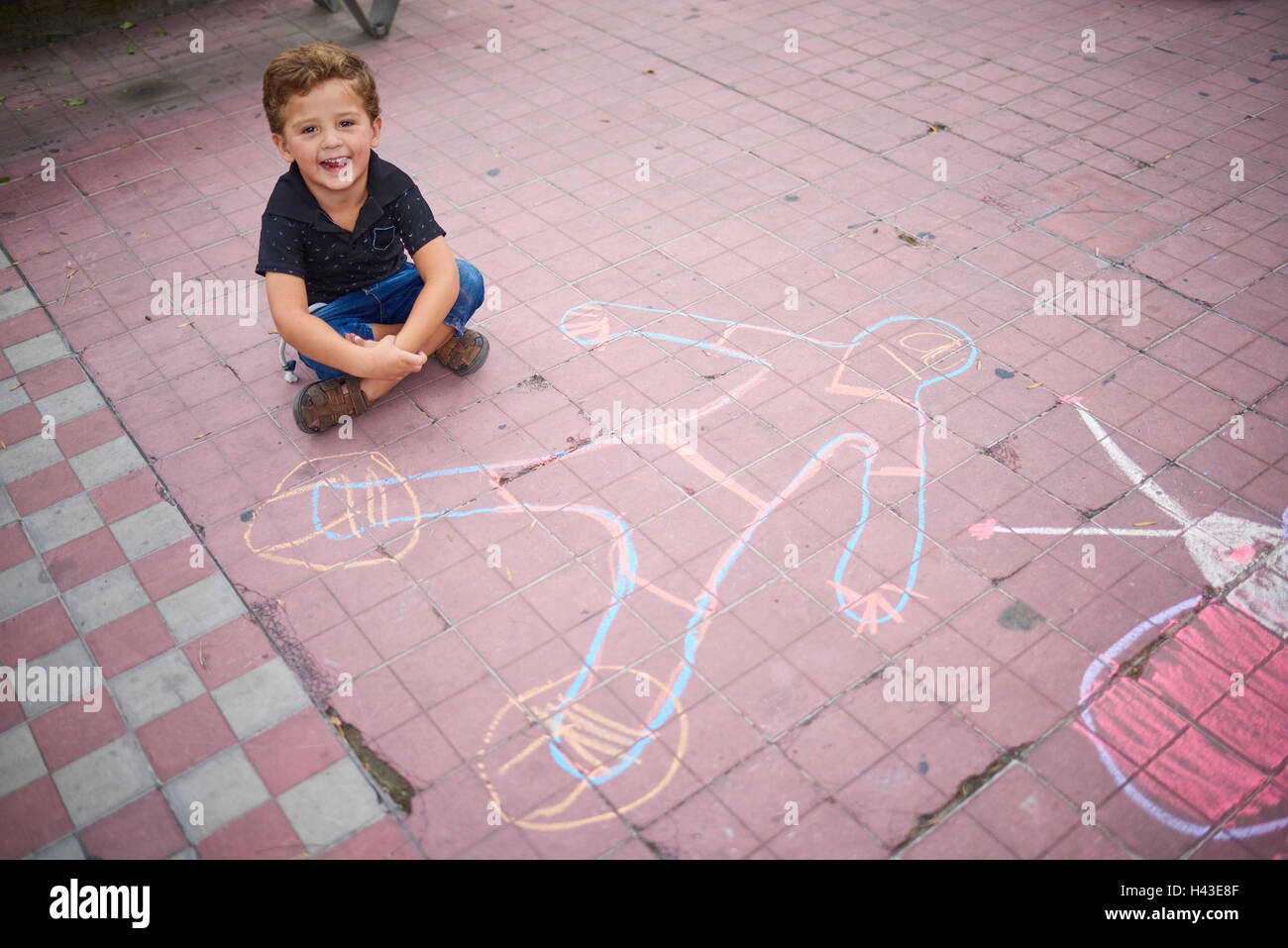 Ragazzo ispanica con chalk disegno sul marciapiede Foto Stock
