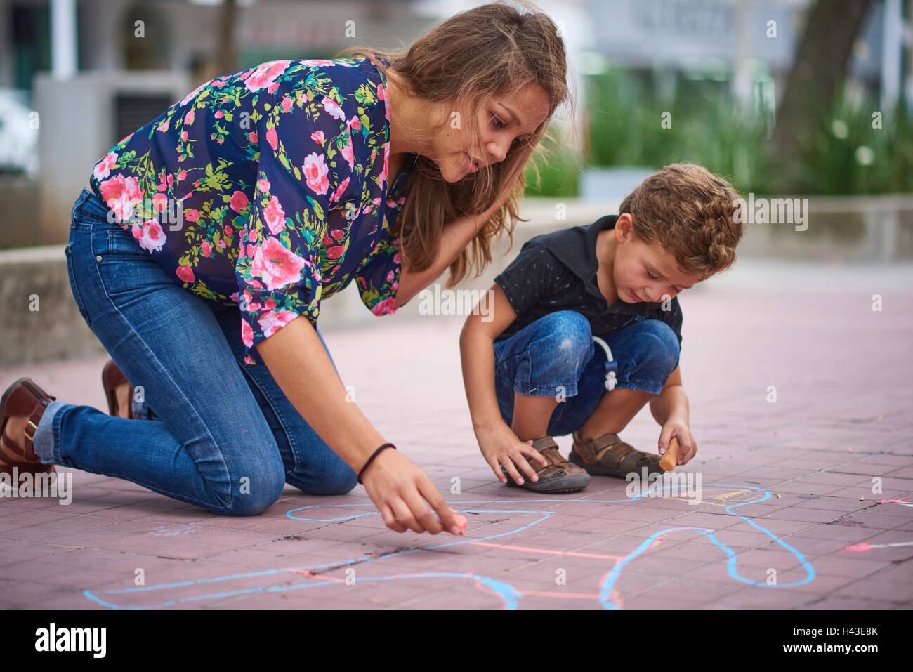 Ispanico madre e figlio il disegno sul marciapiede con Chalk Foto Stock