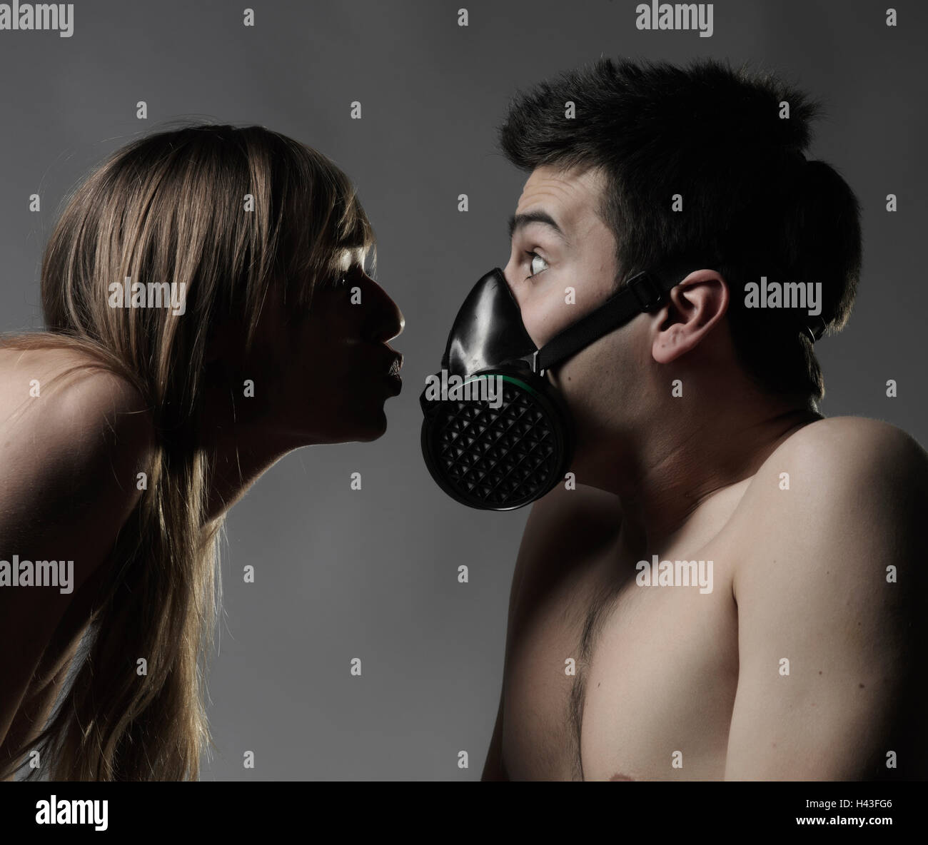 Nudo di donna caucasica la respirazione sull uomo che indossa la maschera di inquinamento Foto Stock