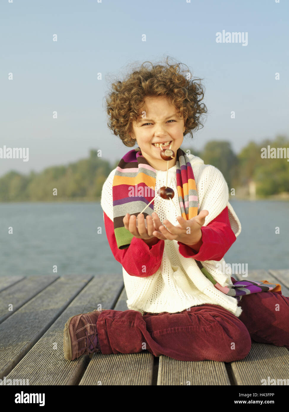 Lago, bridge, bambino, ragazza, play, castagne, figura, punto, orgogliosamente, autunno, acque, pontile in legno, tempo libero, vacanze vacanze autunnali, persone, arricciature ondulate, sciarpa, inginocchiarsi, non solo di artigianato, selftinkered, castagno poco gli uomini, ippocastani, castagno figure, fantasia, creatività, presente, attesa, sorriso, ci grin, dente divario, divertente, stagione, infanzia, interi corpi, natura, esterno, Foto Stock