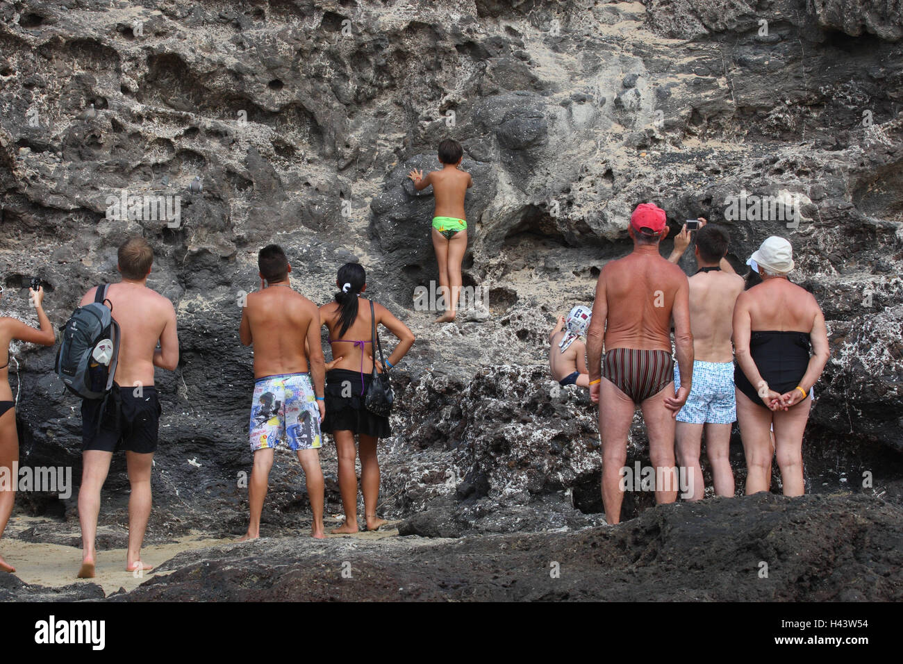 La gente sulla spiaggia osservare rock, vista posteriore, nessun modello di rilascio, Foto Stock