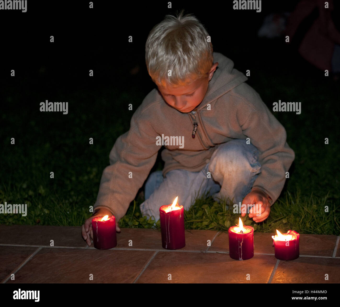 Un ragazzo, gioca con candele, sera fuori, modello rilasciato, Foto Stock