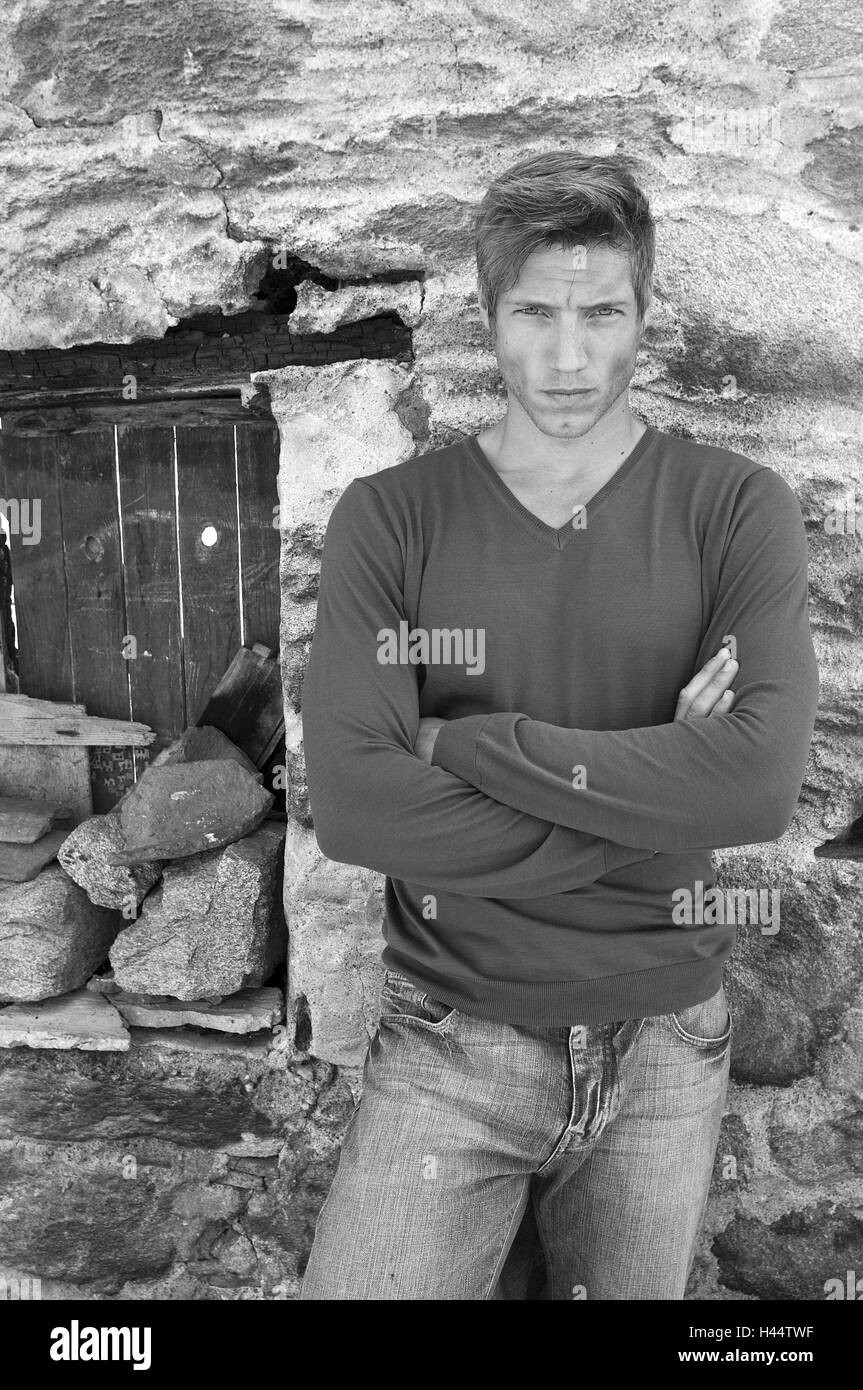 L'uomo, giovani, con le braccia incrociate, pietra muraglia difensiva, stand, b/w, , Foto Stock