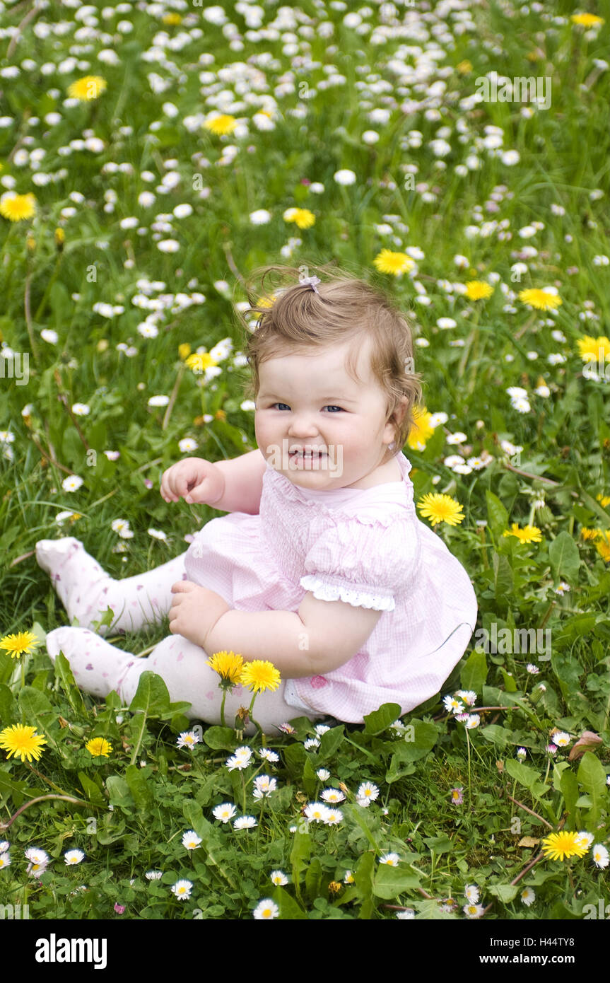 Bambino si siede nel prato di fiori, Foto Stock