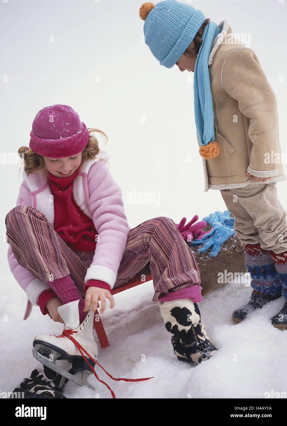 Le ragazze, diapositive, sedersi, disegnare pattini da ghiaccio, boy, guarda, inverni, persone, figli, fratelli, abbigliamento invernale, due tappi, invernale, provare, pattinaggio, sport invernali, interesse, curiosità, Dan livello posizione permanente, freddo, freddamente, stagione, vacanze invernali, gioie invernali, neve, arte neve, tempo libero Tempo libero divertimento, tutto il corpo, studio, Foto Stock