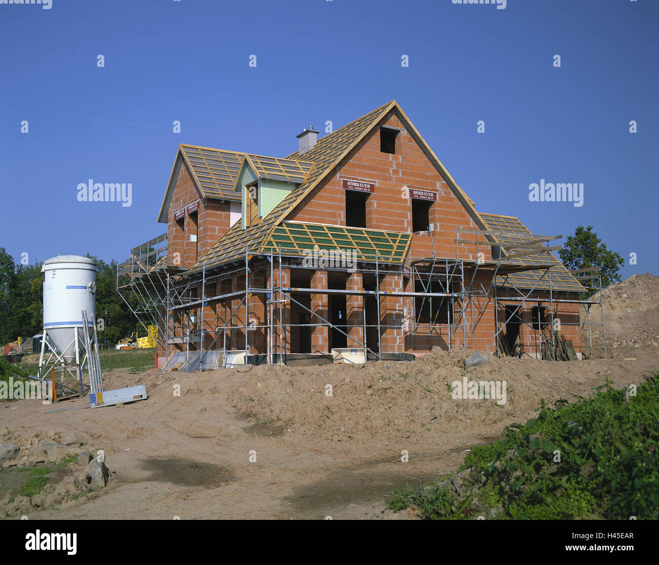 In Germania, in Baviera, la costruzione di una casa, casa unifamiliare, shell, house, costruire muri di fondazione, rivestimenti bitumati, tetto correntini, mattoni rossi, uomini al lavoro, ponteggi, cemento silo, casa di nuova costruzione, settore immobiliare, casa, deserte, fuori casa residenziale, la proprietà di risparmio di costruzione, Foto Stock
