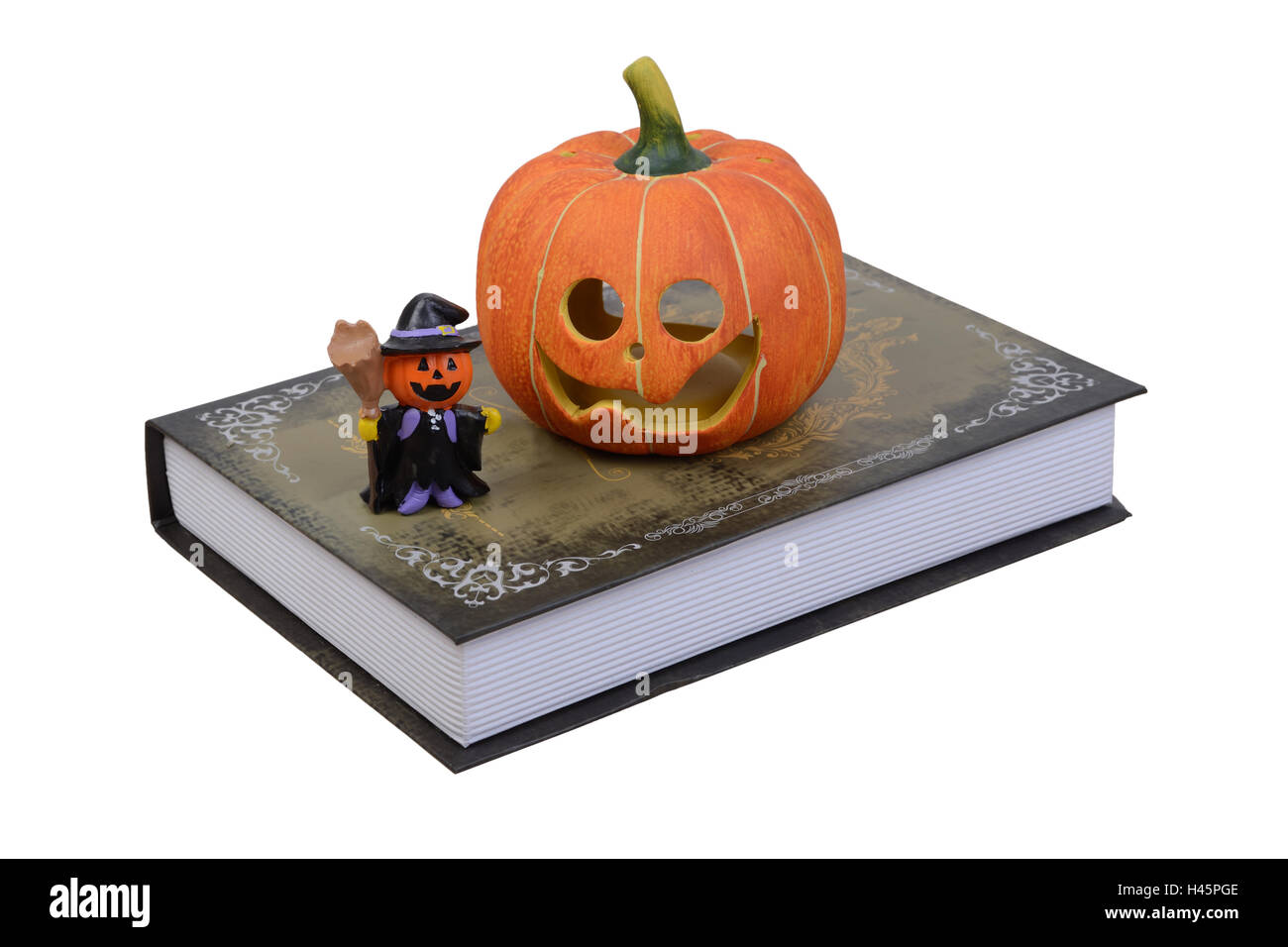 Zucca di Halloween e poco bambola strega immessi sul vecchio libro in uno sfondo bianco. Foto Stock