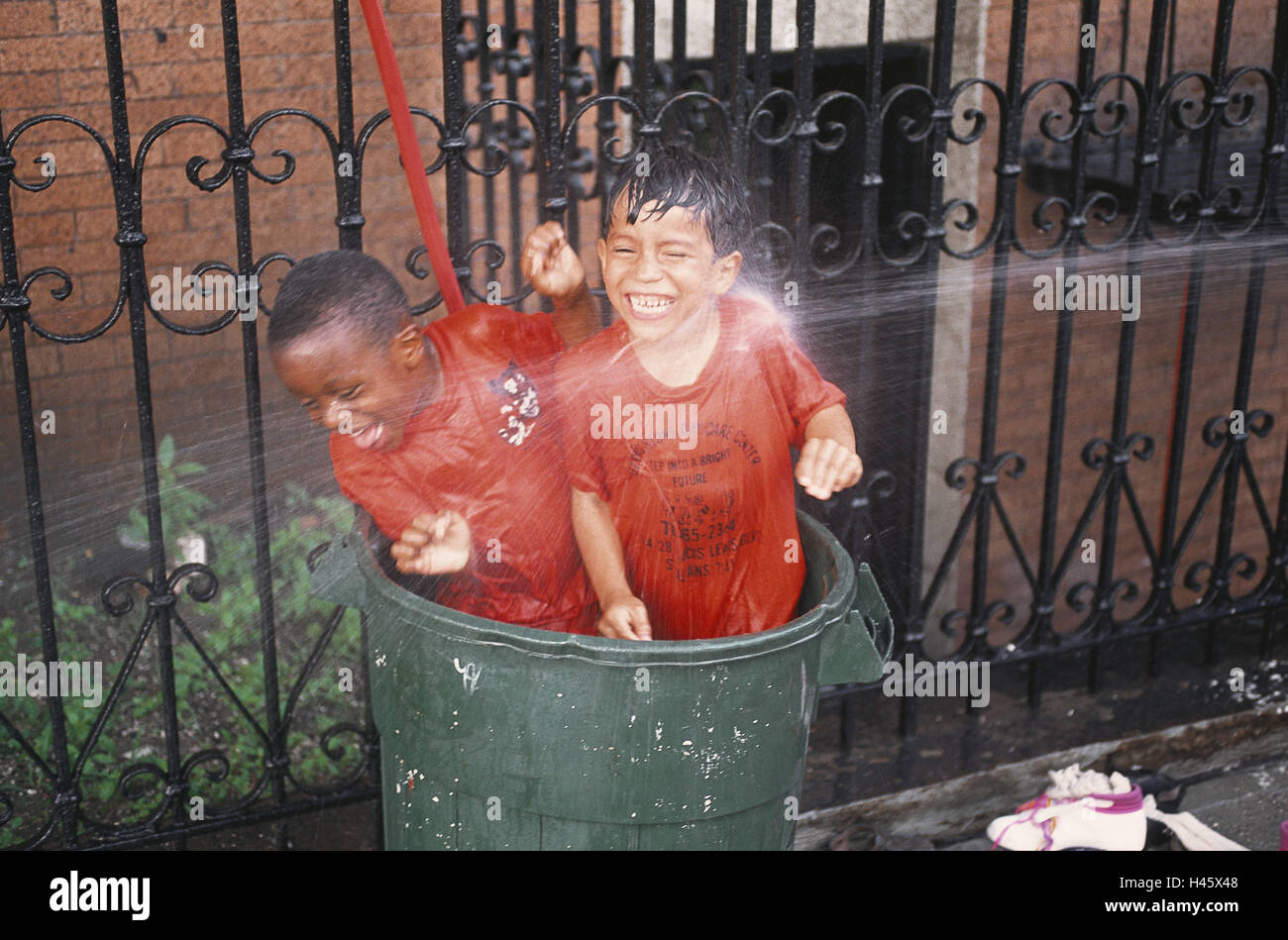 Gli Stati Uniti, New York City, bambini, t, getto di acqua, Bronx, infanzia, divertente, boy, acqua, esterno, persone, bagnato, street, recinzione, ridere, tubo flessibile gioia, raffreddamento, splash, spray, Foto Stock