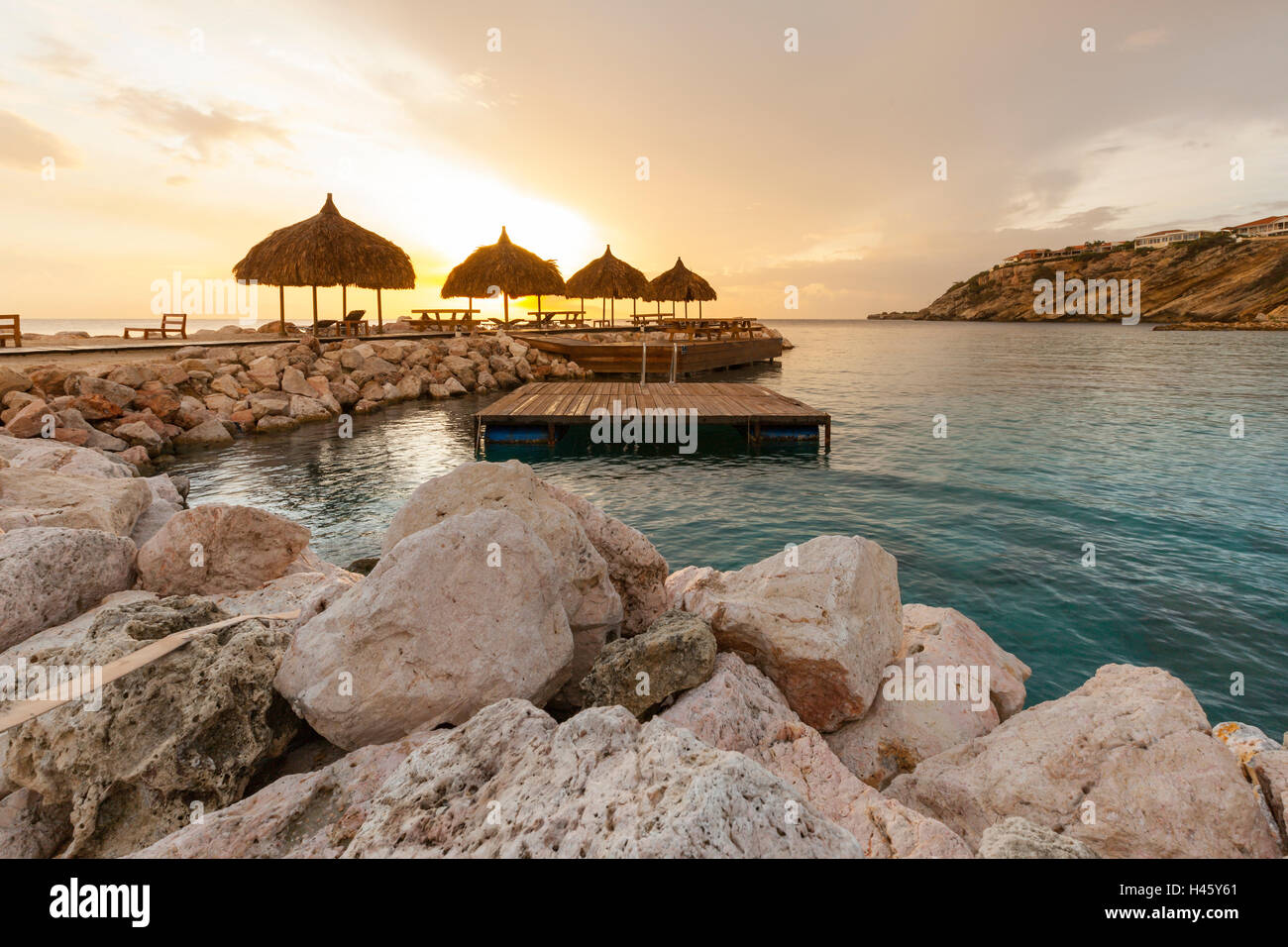 Tramonto dietro cabanas a resort tropicale Foto Stock
