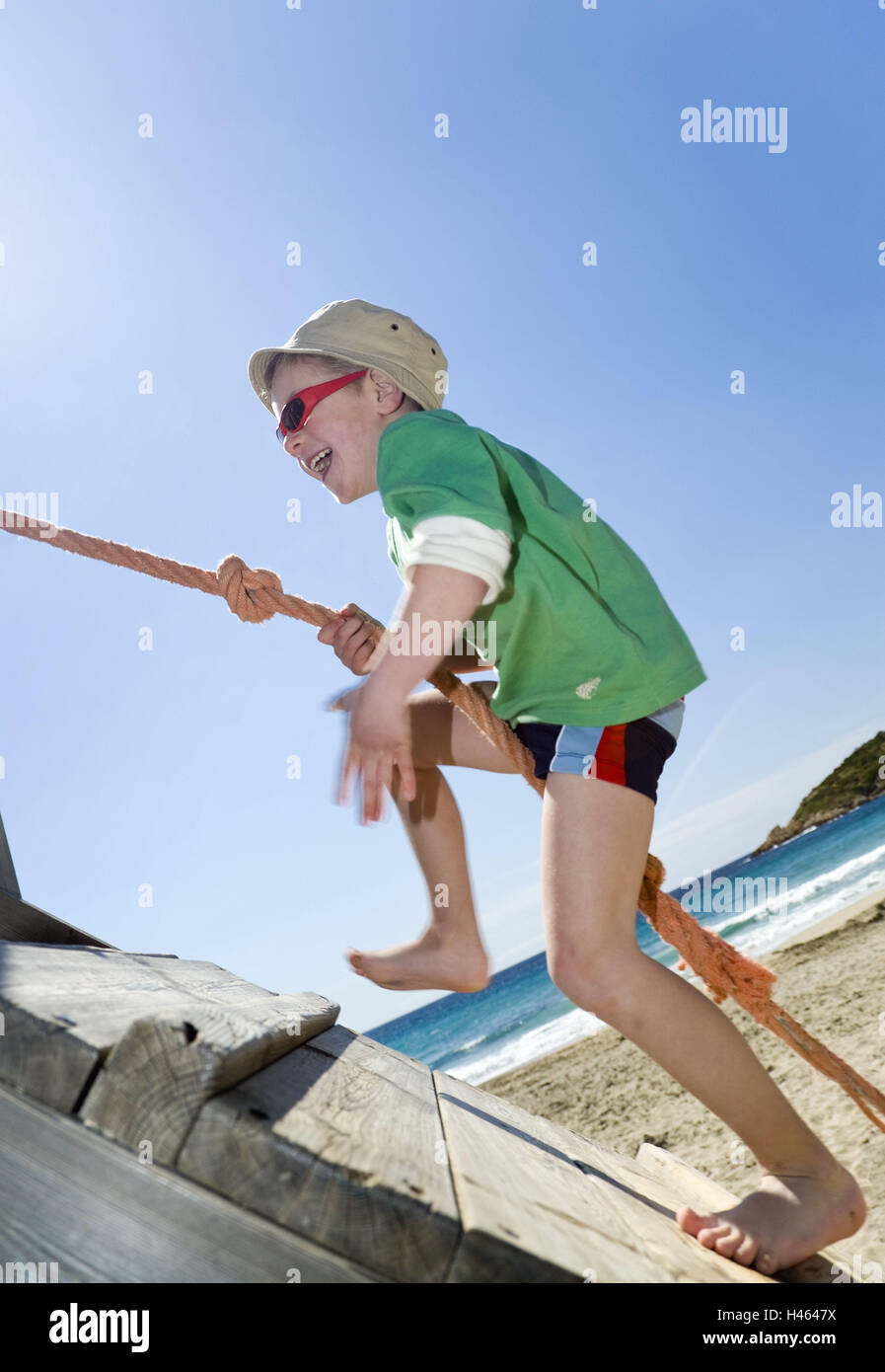 Il ragazzo, felice, arrampicarsi corda, luogo vista laterale, pareti in legno, dettaglio beach, casa da gioco, arrampicata help, promozione, climbing frame, parco giochi, Su, Su, ripidamente, divertente, gioia, gioco, gioco, fuso, sorriso, cura, solare, cappello, occhiali da sole, mare, scalzi, infanzia, tempo libero, copricapo, soleggiato, persone Foto Stock