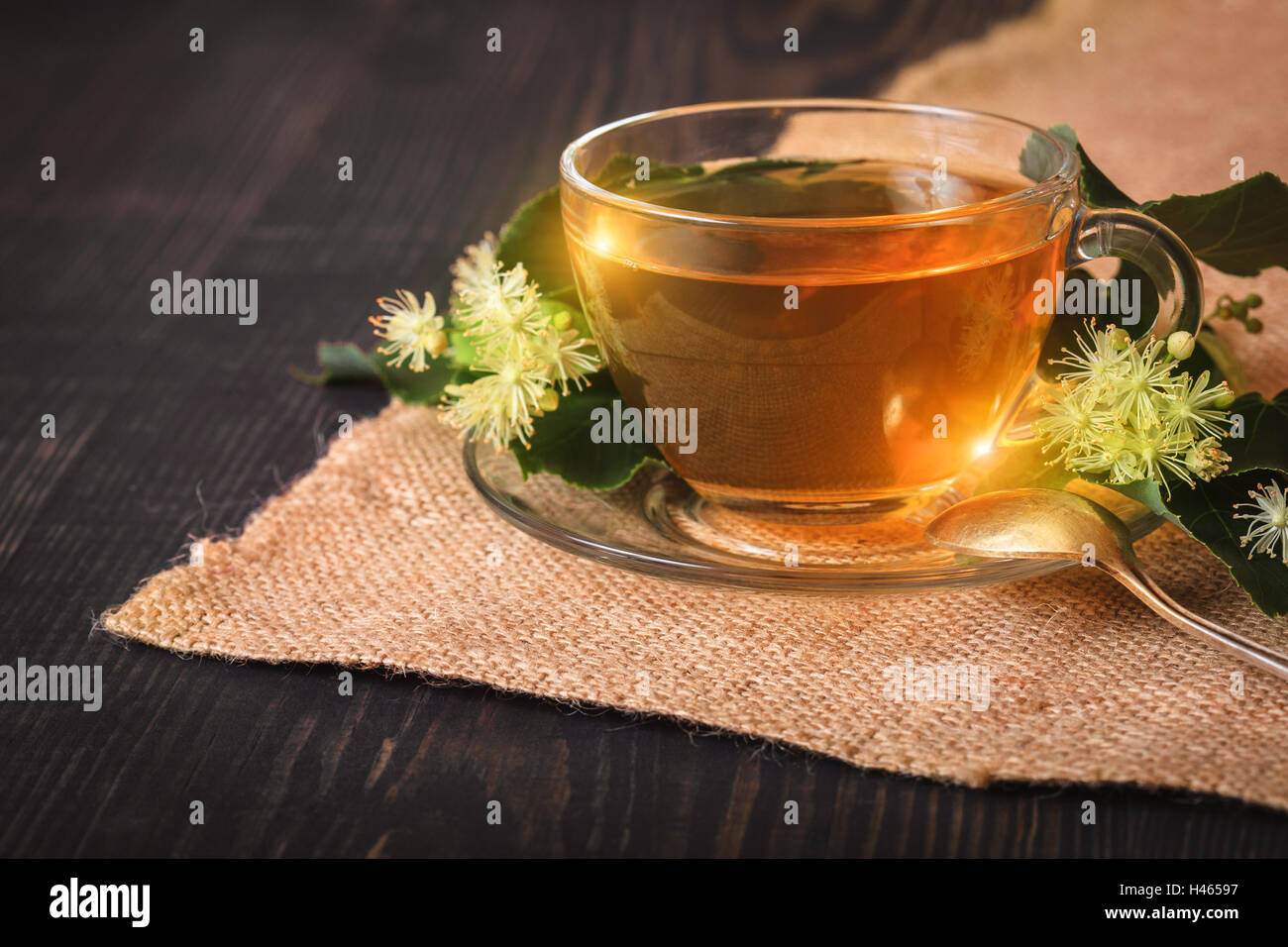 Linden tè su una tavola di legno in un bicchiere di vetro. Fiore di tè, la medicina di erbe. Foto Stock