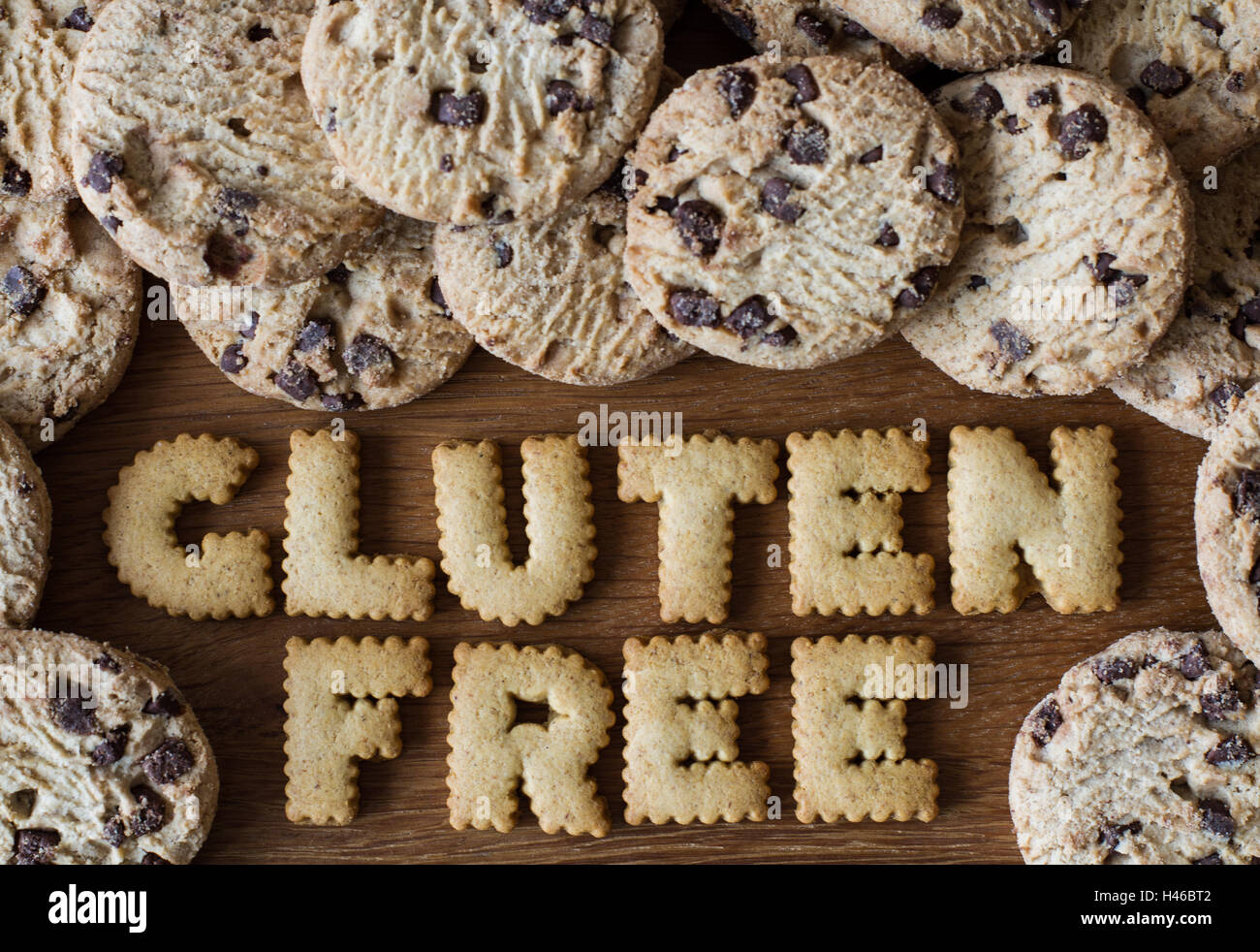 Il cibo consigli "senza glutine" scritto con alfabeto cookie sagomato e circondato da senza glutine, biscotti con scaglie di cioccolato su legno Foto Stock
