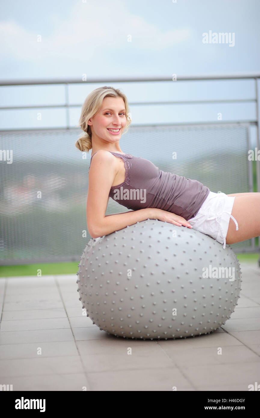 Giovane donna su una sfera di ginnastica, Foto Stock