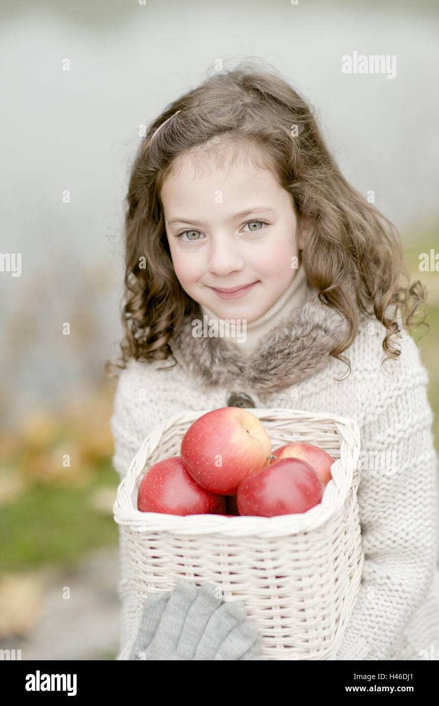 Piccola ragazza porta di un cestello con mele, Foto Stock