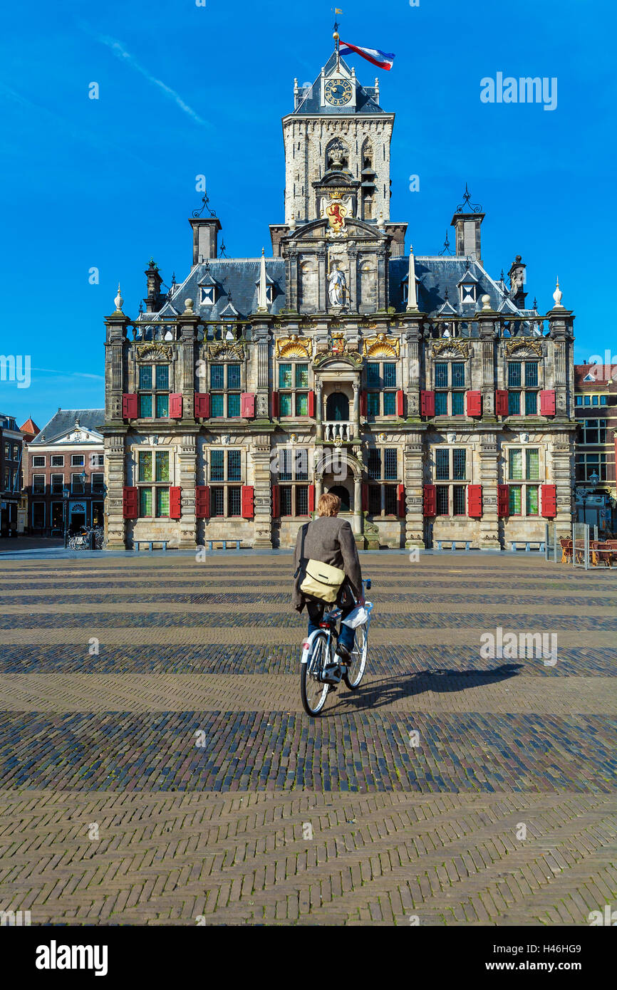 DELFT, Paesi Bassi - 4 Aprile 2008: giovane uomo cavalca una bicicletta vicino edificio del Consiglio (Stadhuis) sulla piazza centrale Foto Stock