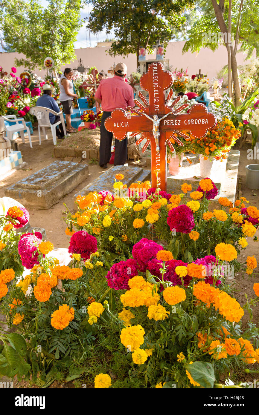 La gente di socializzare tra tombe decorate con elaborati floreali arazzi del pedale in onore del defunto al San Antonino Castillo cimitero durante il Giorno dei Morti Festival noto come D'un de Muertos il 3 novembre 2013 a San Antonino Castillo Velasco, Oaxaca, Messico. Foto Stock