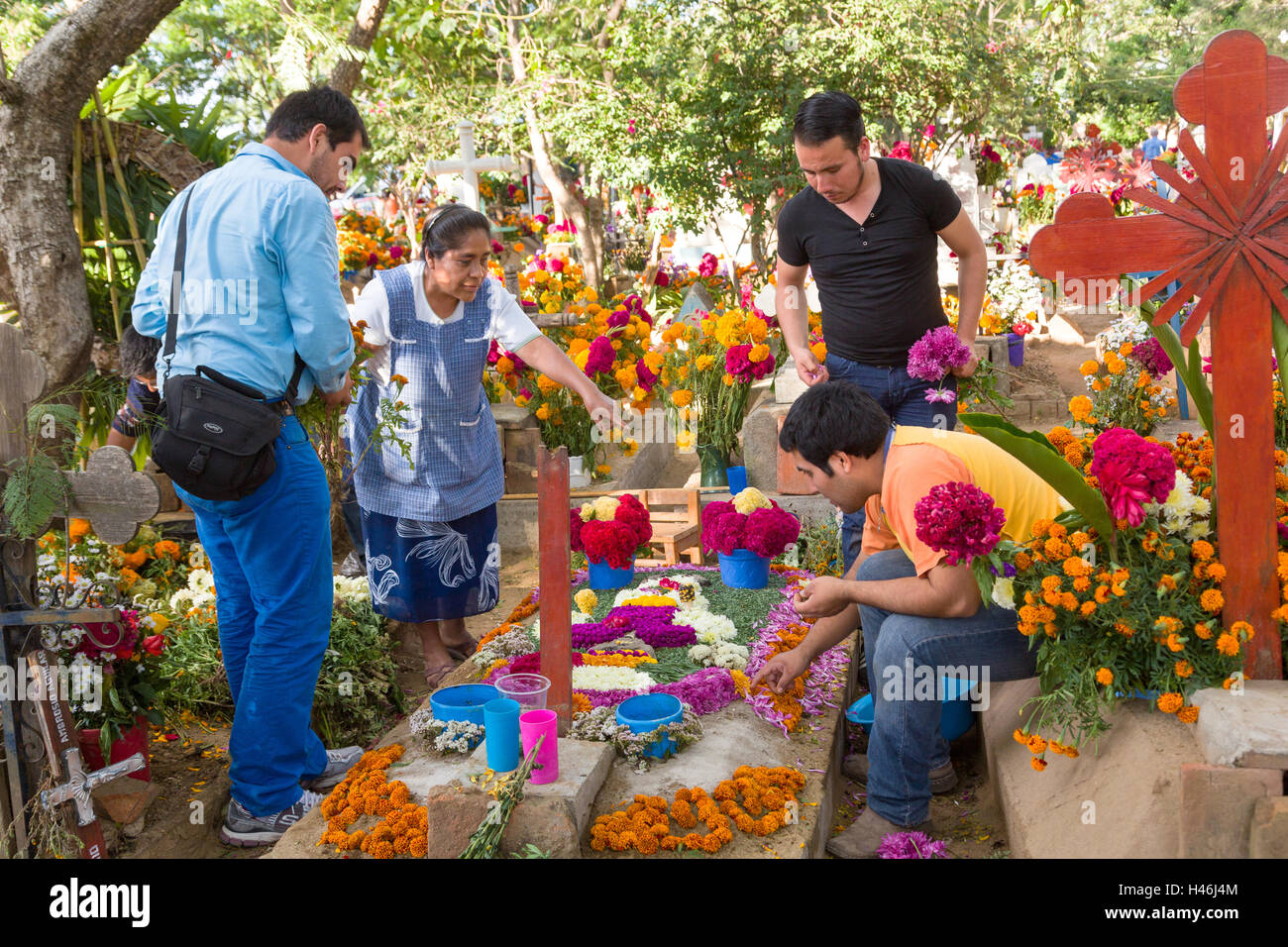 Persone decorate a tombe con elaborati floreali arazzi del pedale in onore del defunto al San Antonino Castillo cimitero durante il Giorno dei Morti Festival noto come D'un de Muertos il 3 novembre 2013 a San Antonino Castillo Velasco, Oaxaca, Messico. Foto Stock