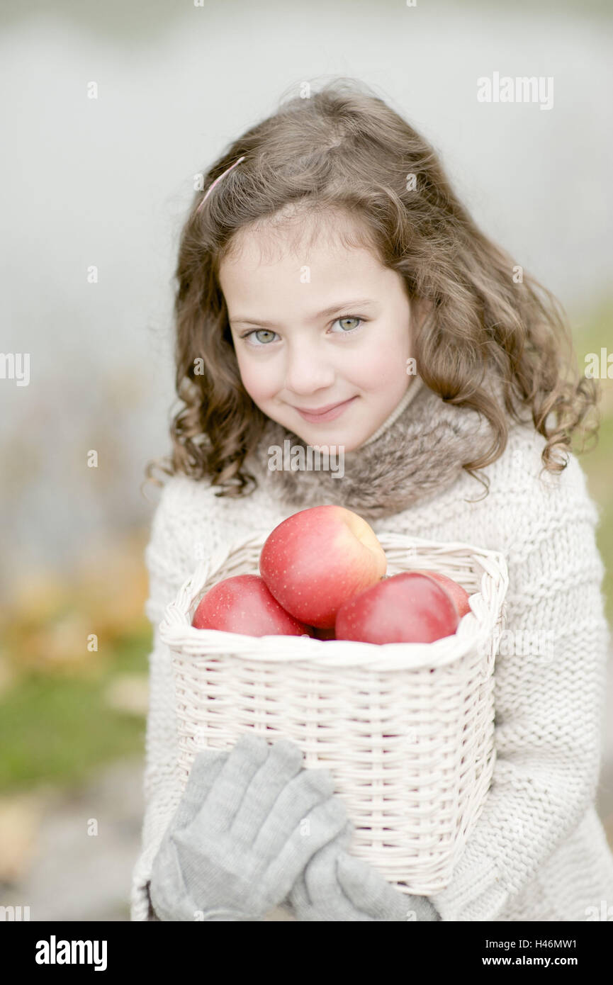 Bambina sta portando un cesto con mele, Foto Stock
