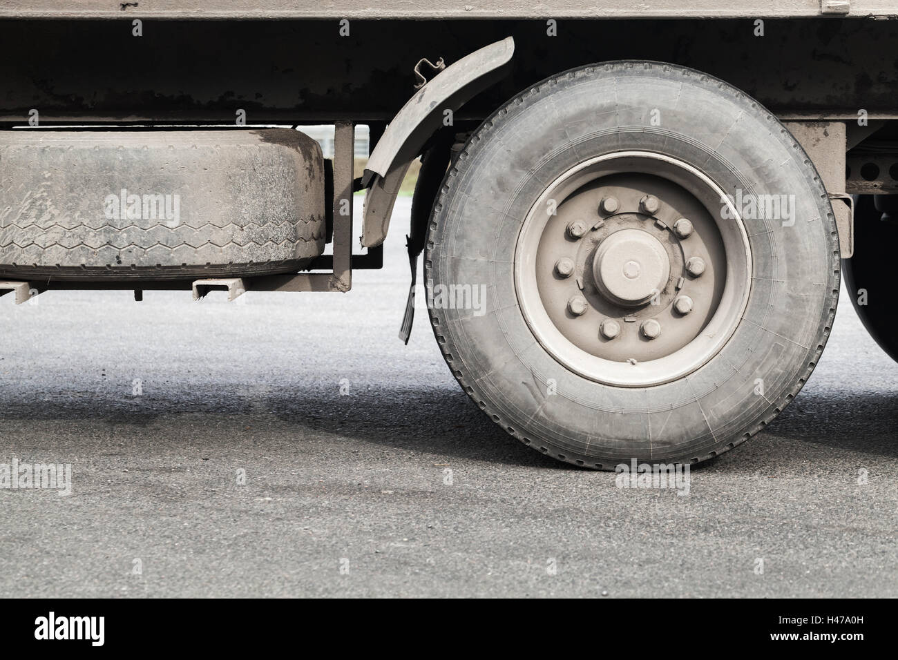 Le ruote sporche di camion su GRIGIO ASFALTO Foto Stock