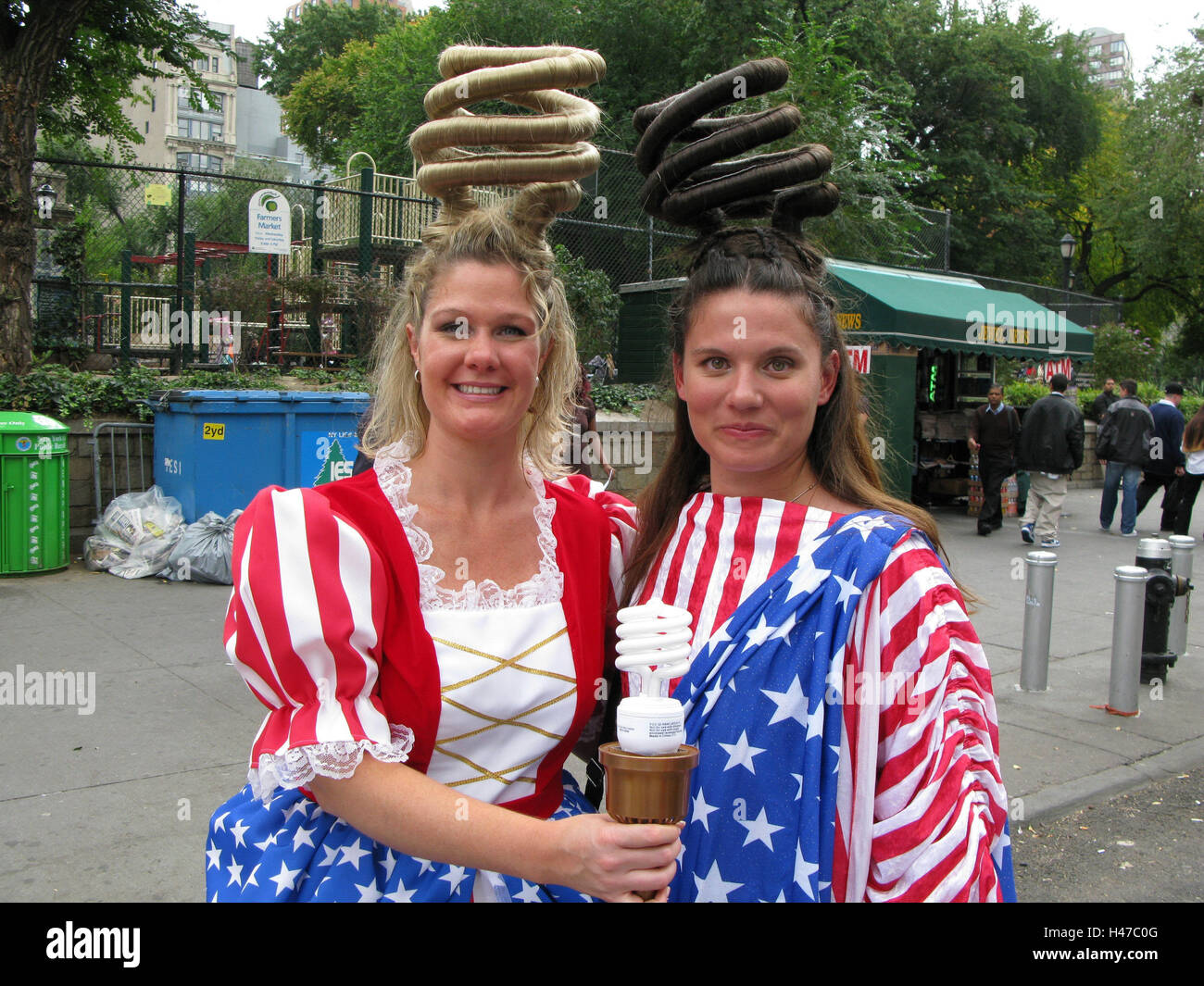 Gli Stati Uniti, New York City, donne, due, fodera, sorriso, conquistare annuncio, economia lampade, ritratto, America, Nord America, persona, americani, giovani, promozione, pubblicità, campagna pubblicitaria, alla promozione delle vendite, peli, capelli, la forma a spirale, ruotato e arguzia, lampadine, energia, presentazione, vestiti, bandiera, abito, in maniera americana, chiosco, esterno, Foto Stock