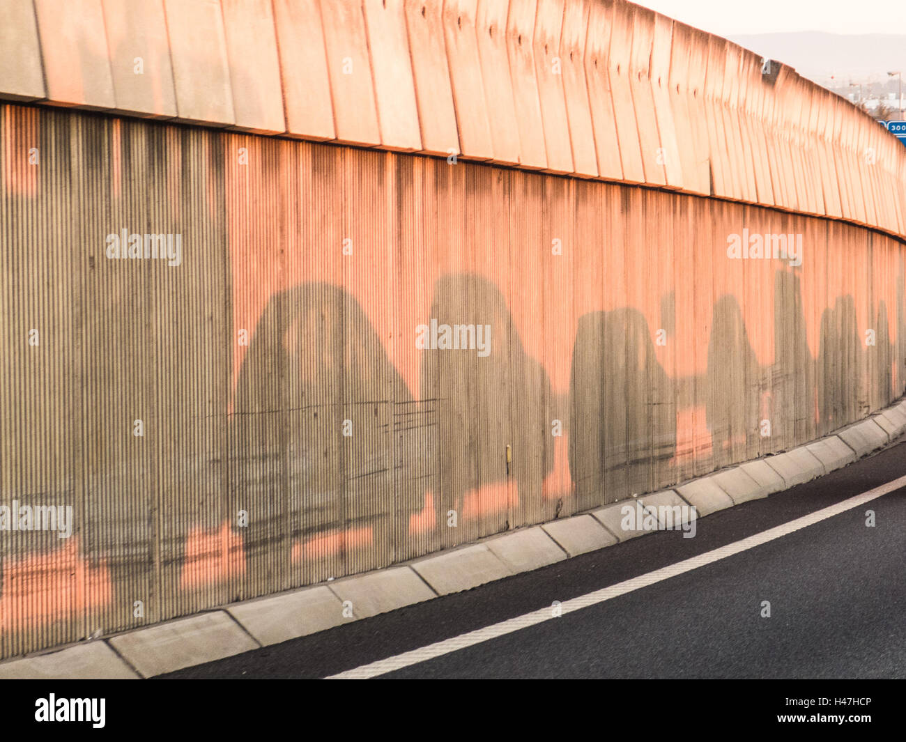 Ombre di automobili nel sole mattutino su una barriera lungo una strada andando a Siviglia. C'è un ingorgo stradale durante la mattina Foto Stock