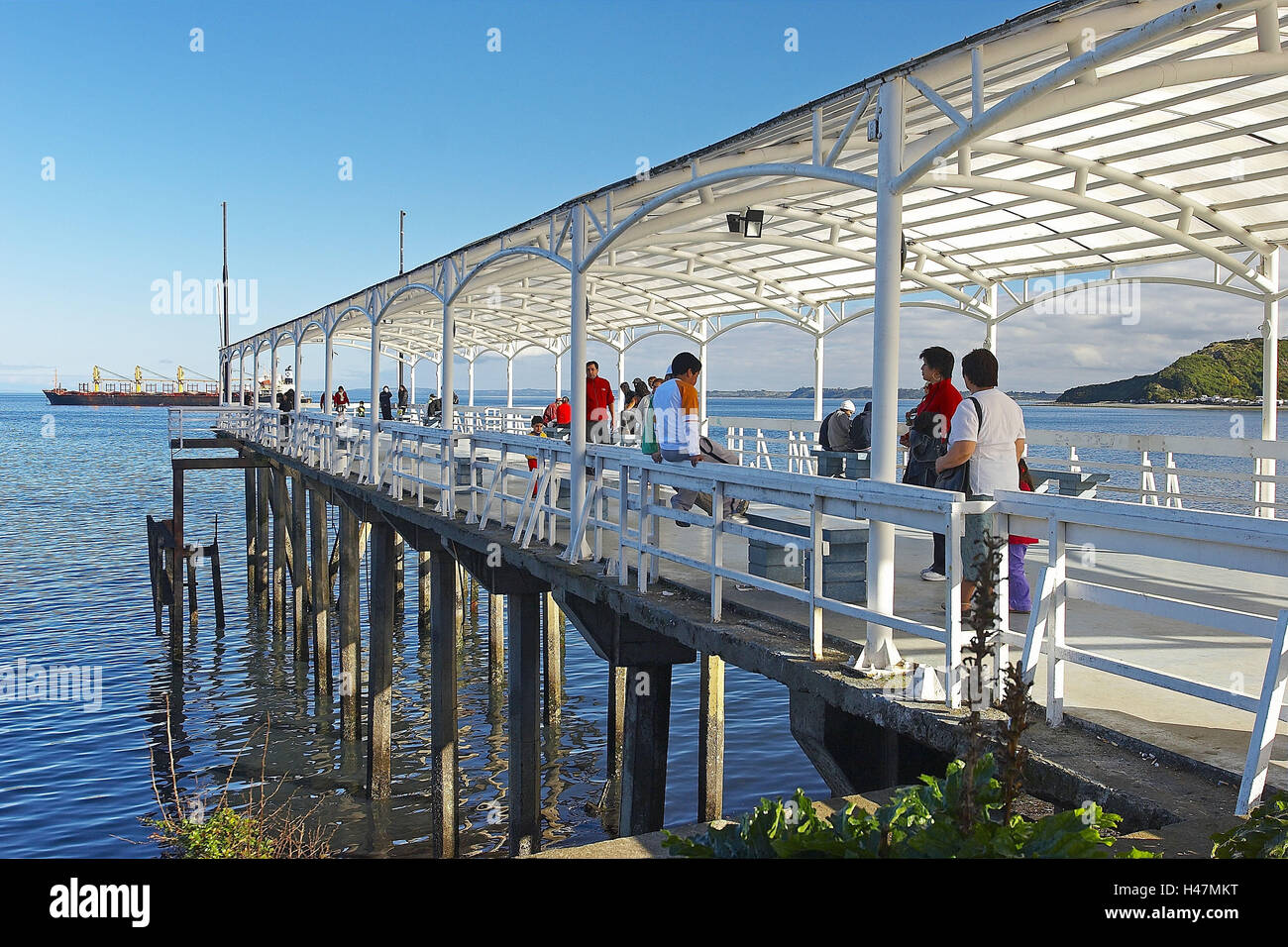 Sud America, Cile, Patagonia, Puerto Montt, banca promenade, pier, persone cargo in background, Foto Stock
