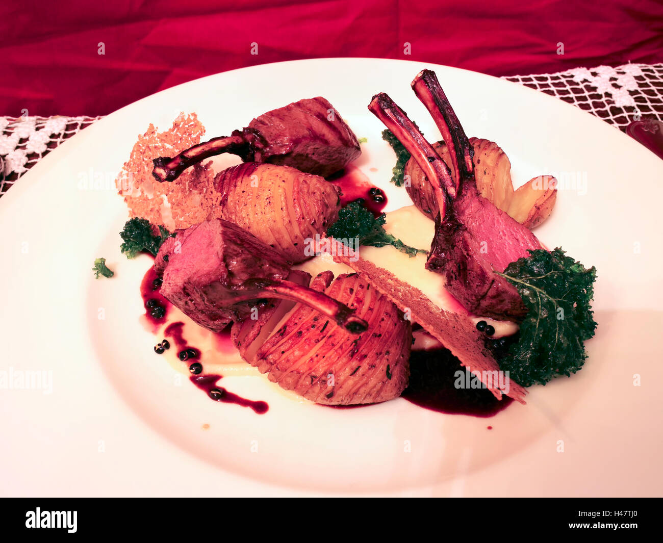 Sella di grigliate di carne di cervo con ossa servito con patate arrosto, sugo sulla piastra bianca Foto Stock