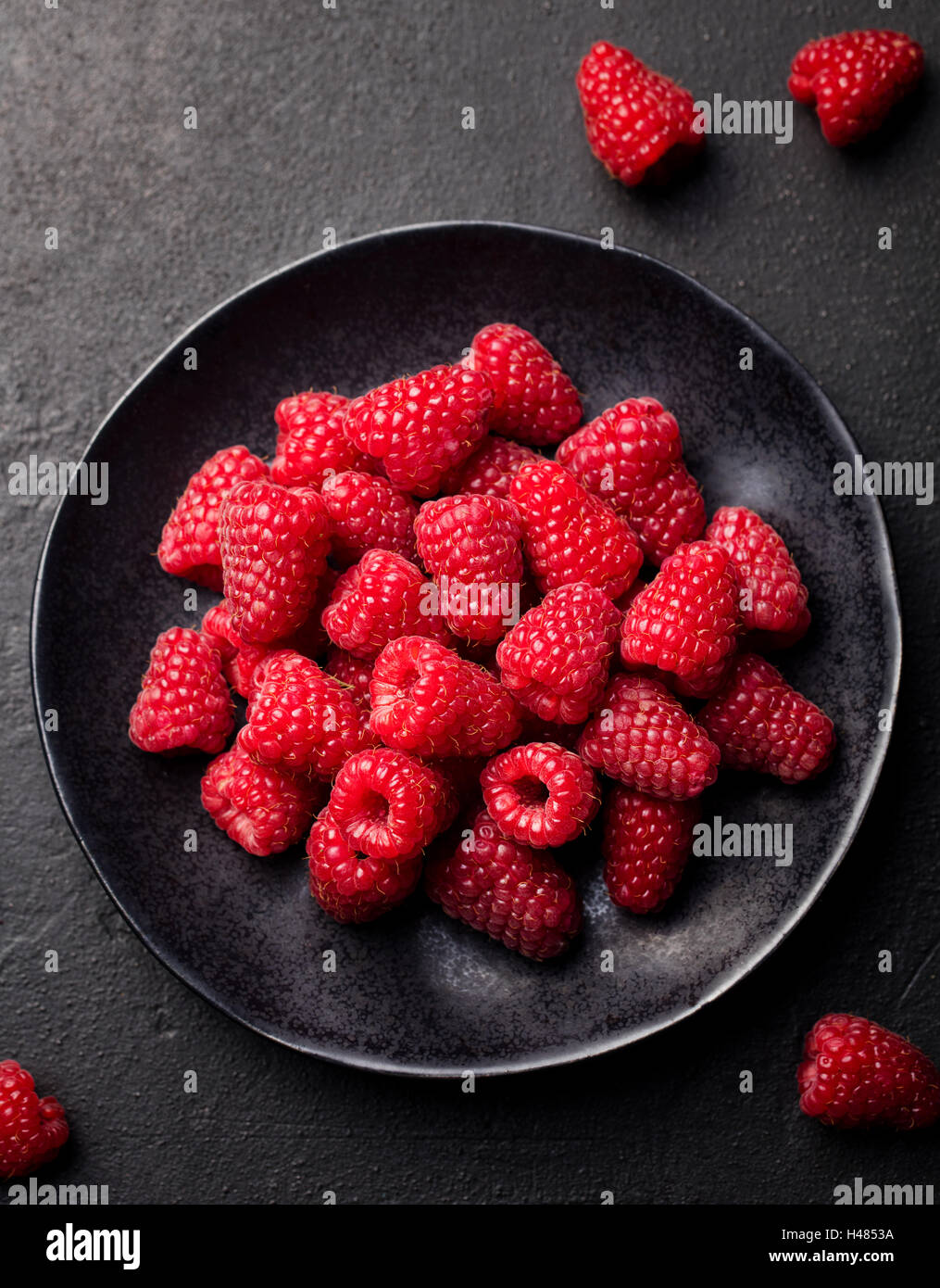 Lamponi freschi su una ciotola nero. Vista superiore Foto Stock