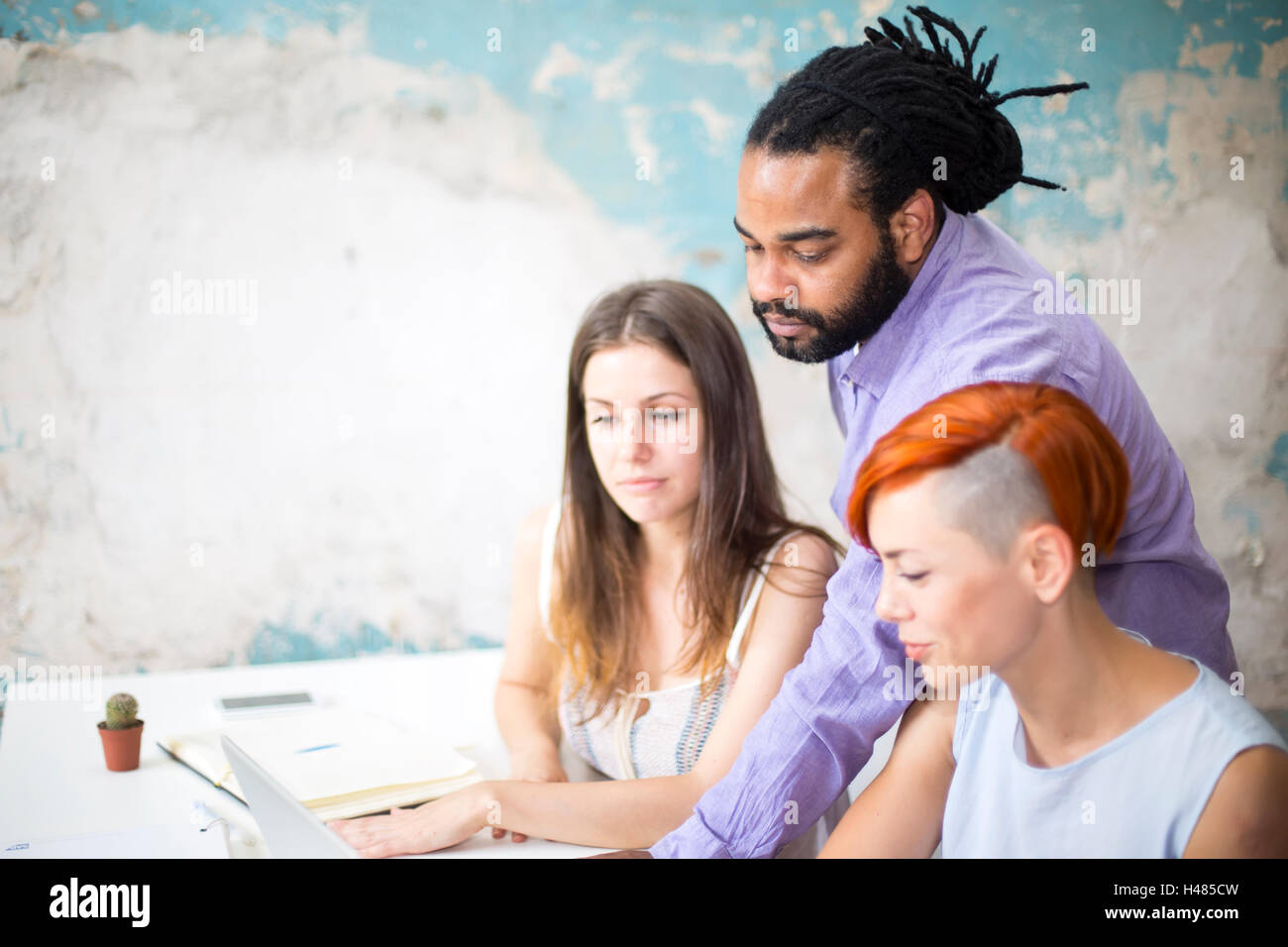 Giovani multirazziale persone che lavorano con la scrivania in ufficio grunge Foto Stock