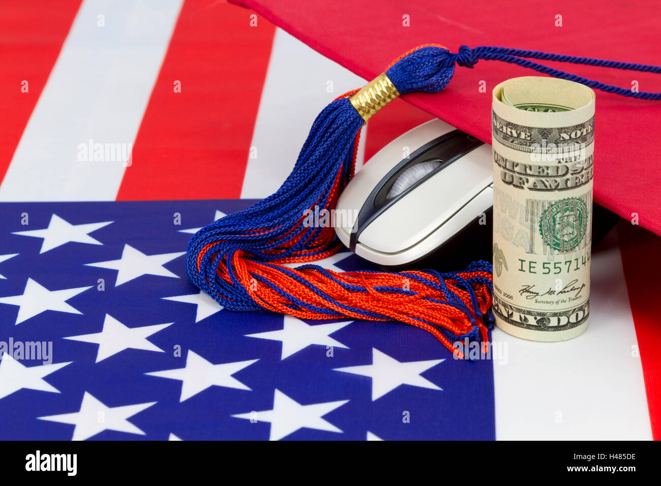 Graduazione calotta disposta con il mouse del computer e la valuta del dollaro sulla bandiera americana pattern. Foto Stock