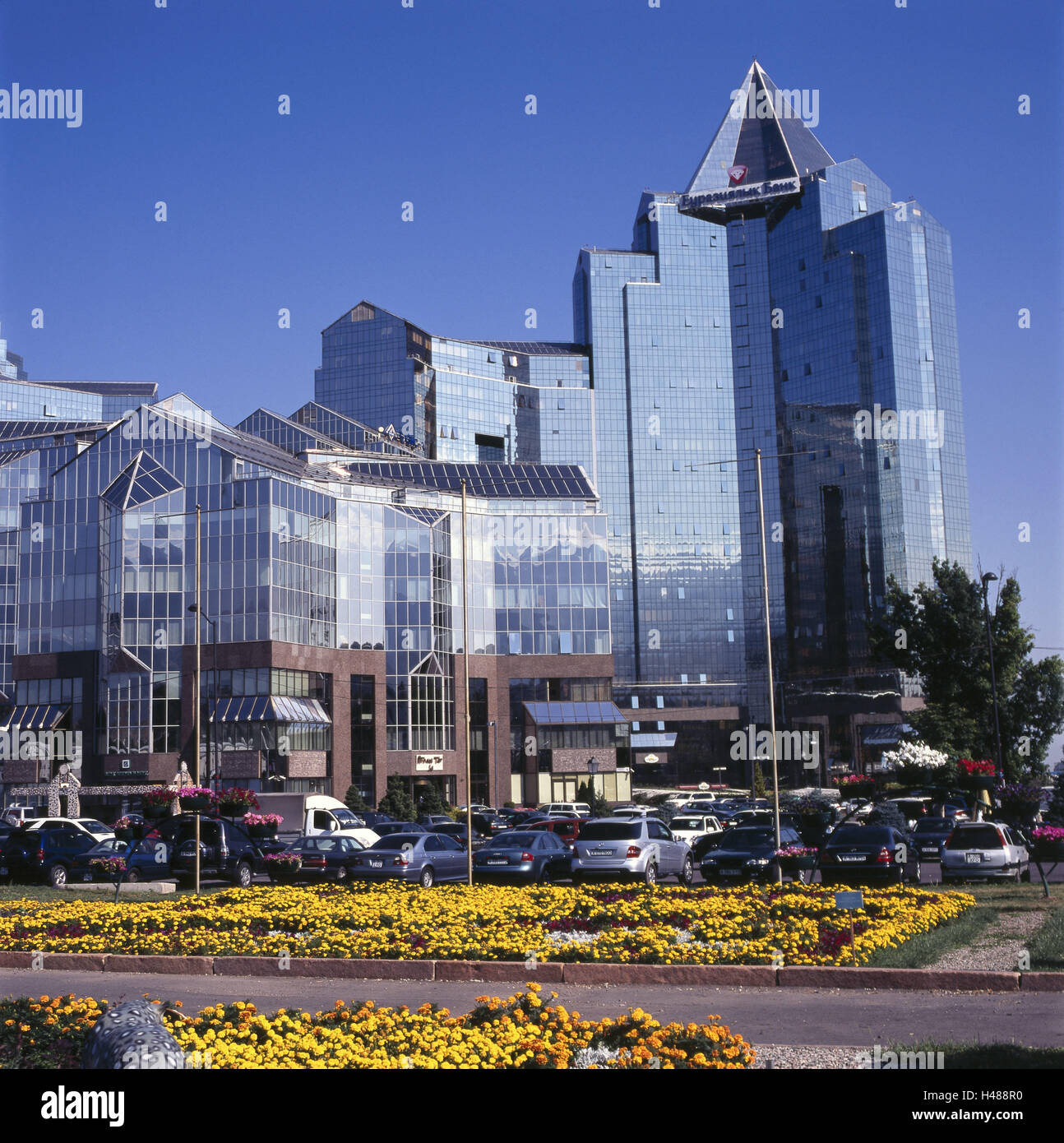 Il Kazakistan, Almaty, banca, fuori, edificio, facciata, vetro anteriore, cielo blu, finanze, parcheggio, veicoli, fiori, Foto Stock