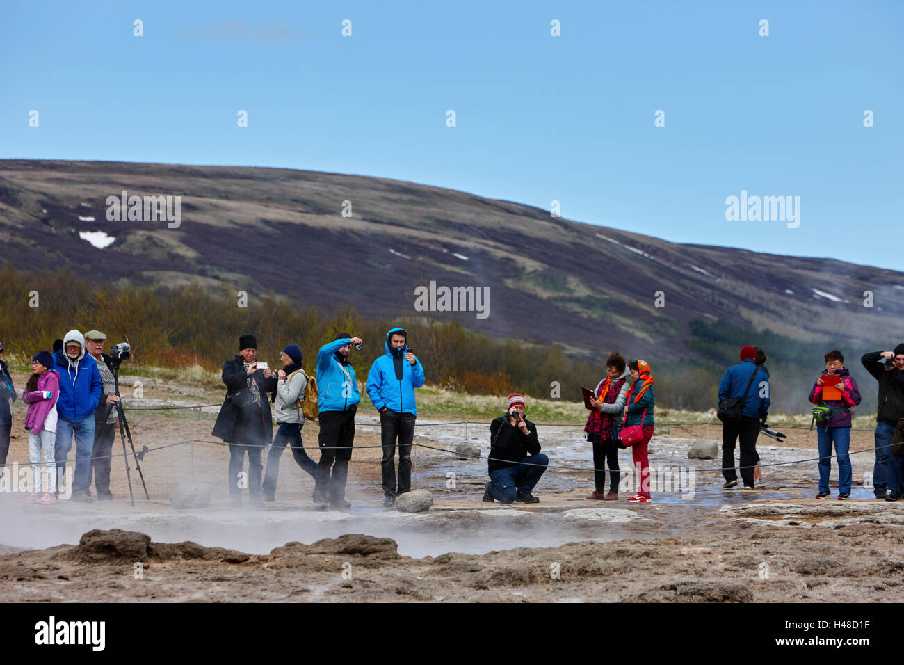 I turisti stanno intorno in attesa per la strokkur geyser a scatenarsi geysir Islanda Foto Stock