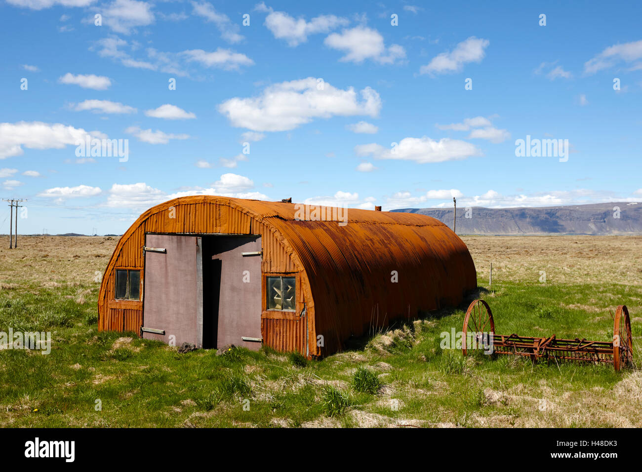 Vecchia ruggine nissen hut su terreno coltivato in Islanda Foto Stock