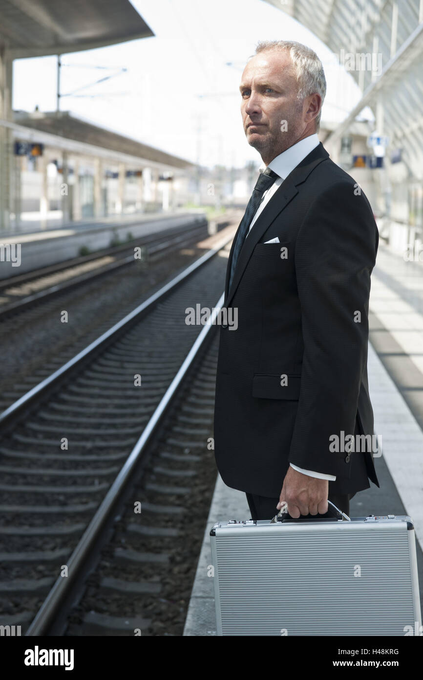 Manager con valigetta sta aspettando nel binario ferroviario, Foto Stock