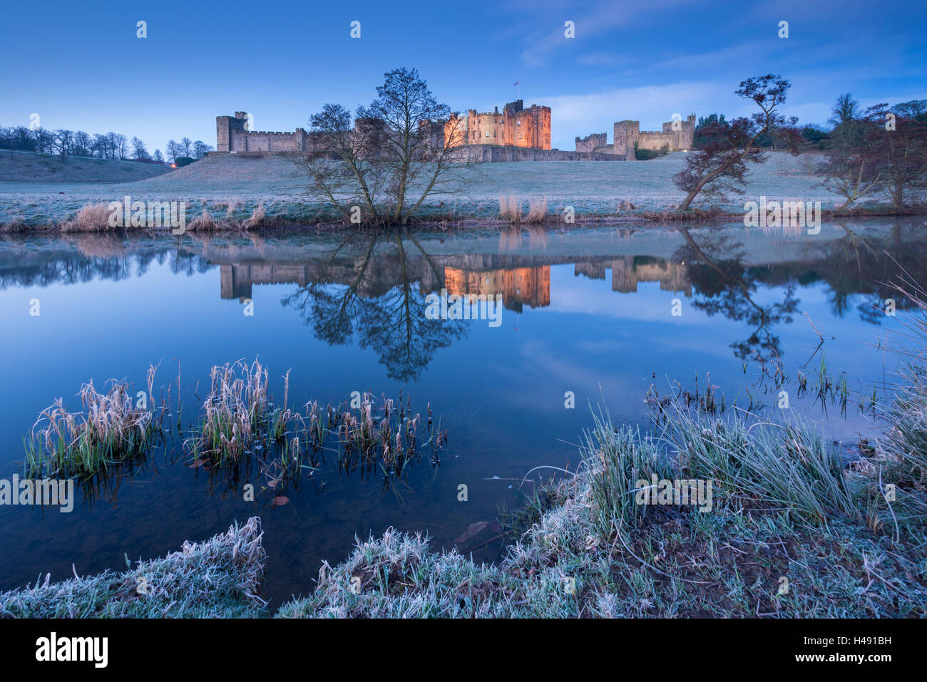 Alnwick Castle riflessa nel fiume Aln su un gelido inverno mattina, Northumberland, Inghilterra. Inverno (Marzo) 2014. Foto Stock