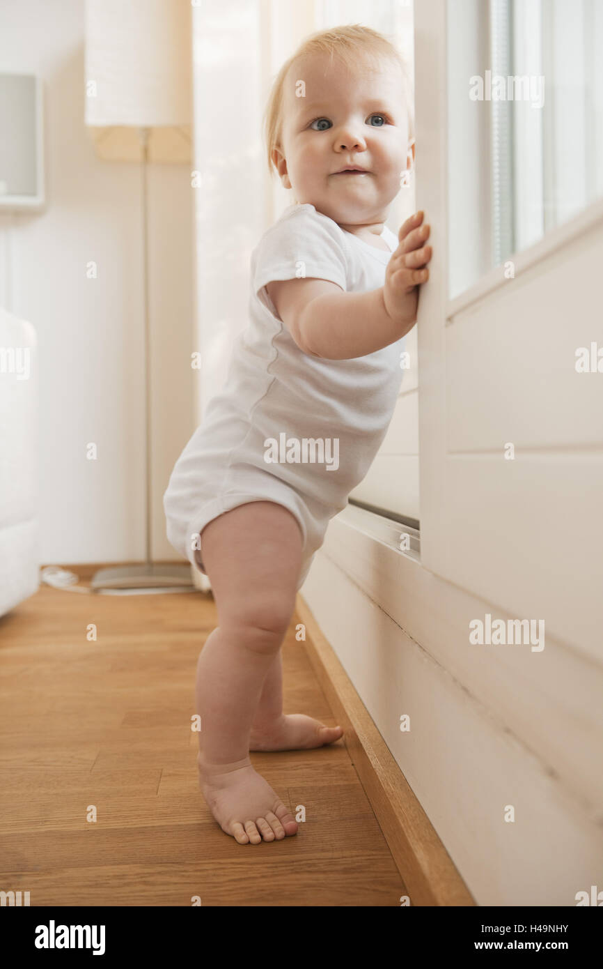 Baby, 1 anno di età, in piedi presso la finestra Foto Stock